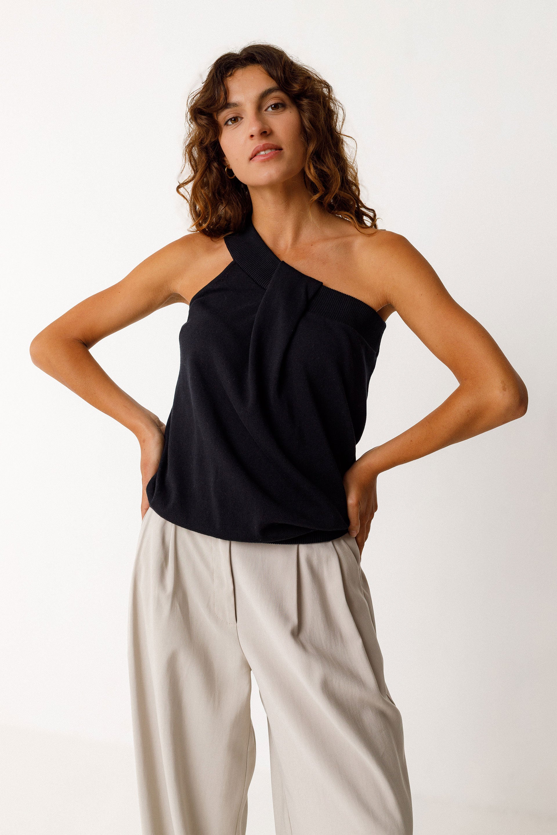 Woman wearing a black halter top and beige pants on a white background