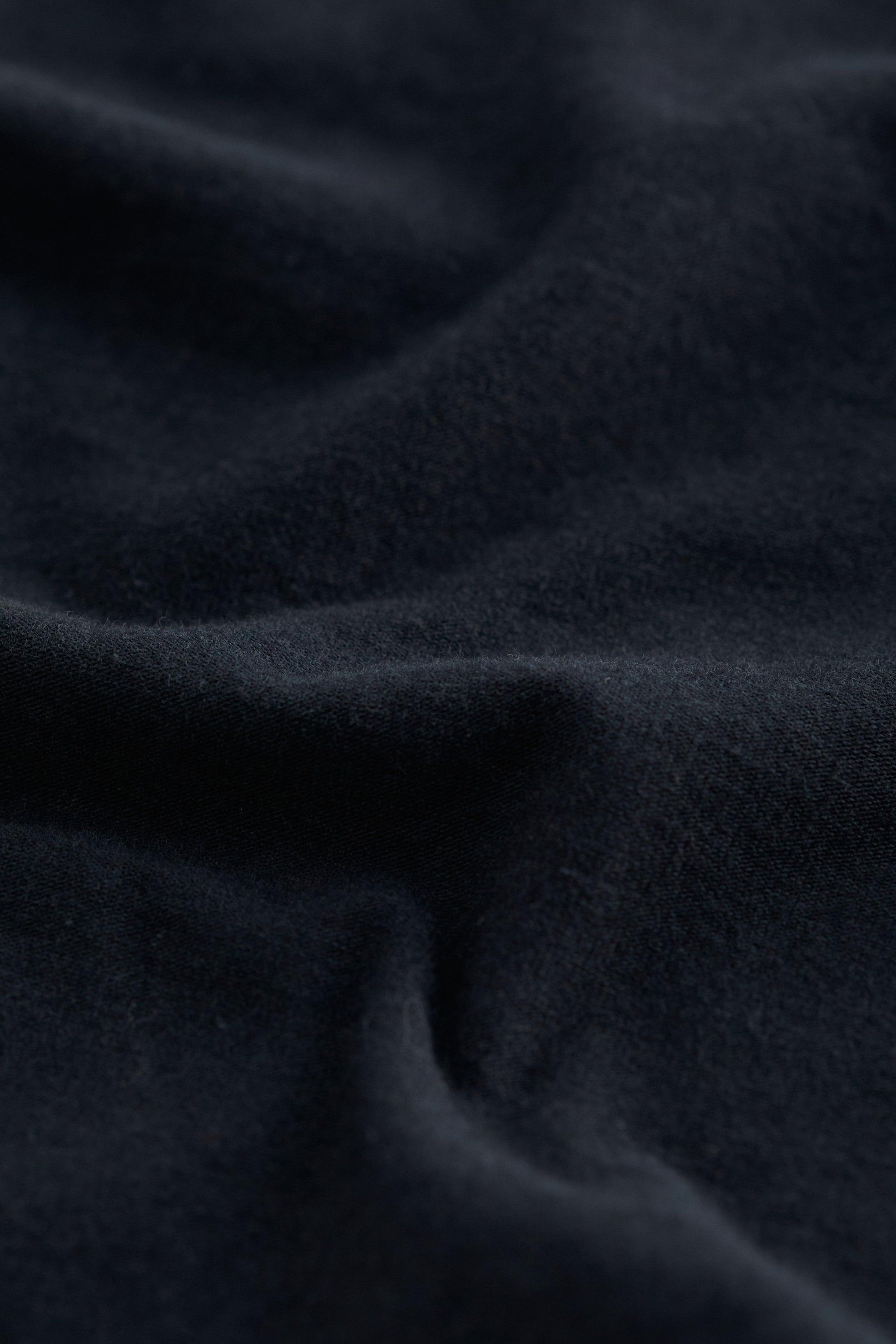 A close-up of dark navy blue fabric with soft folds and a smooth, slightly textured surface.