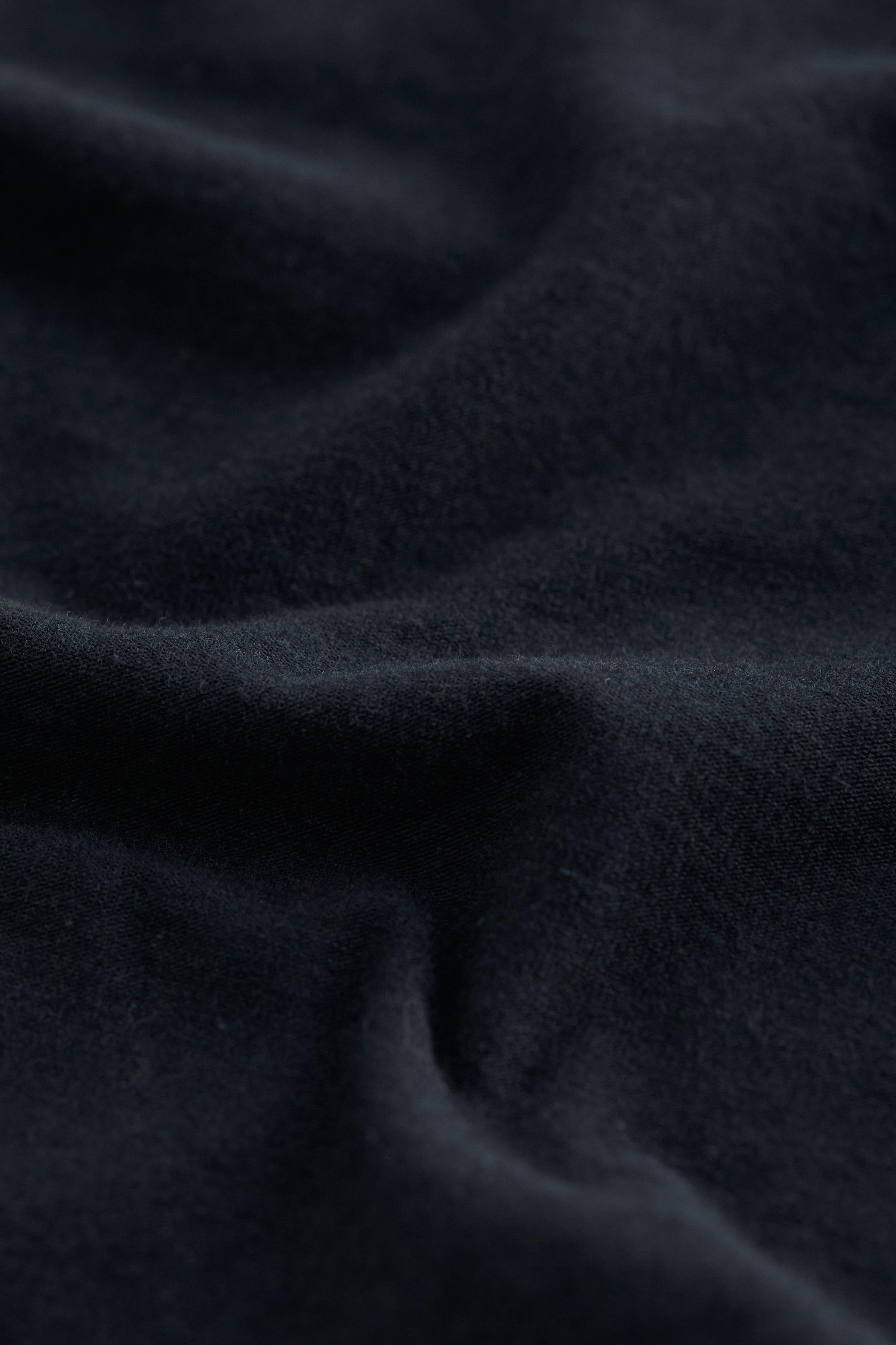 A close-up of dark navy blue fabric with soft folds and a smooth, slightly textured surface.