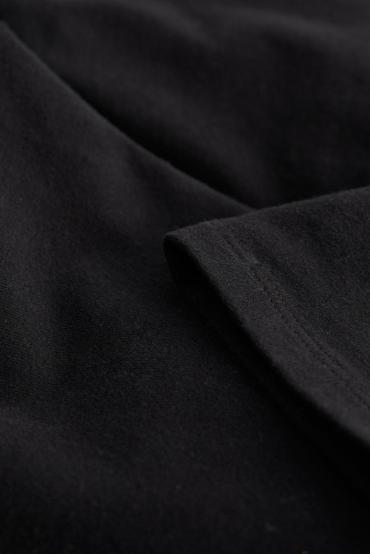 Close-up of black organic cotton fabric showing the smooth texture and stitching of Seasalt Cornwall women's leggings.