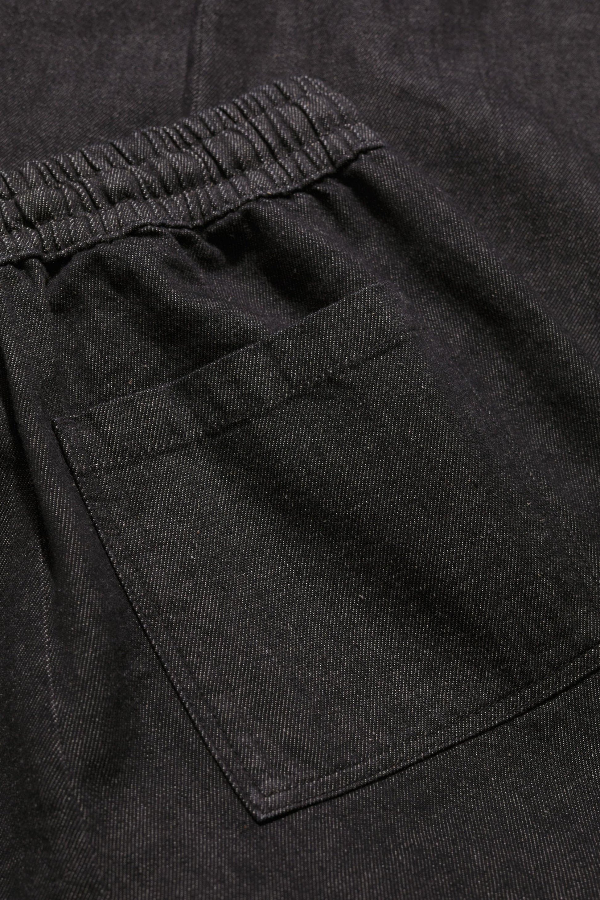 Close-up of a black organic cotton trouser pocket with an elasticated waistband.