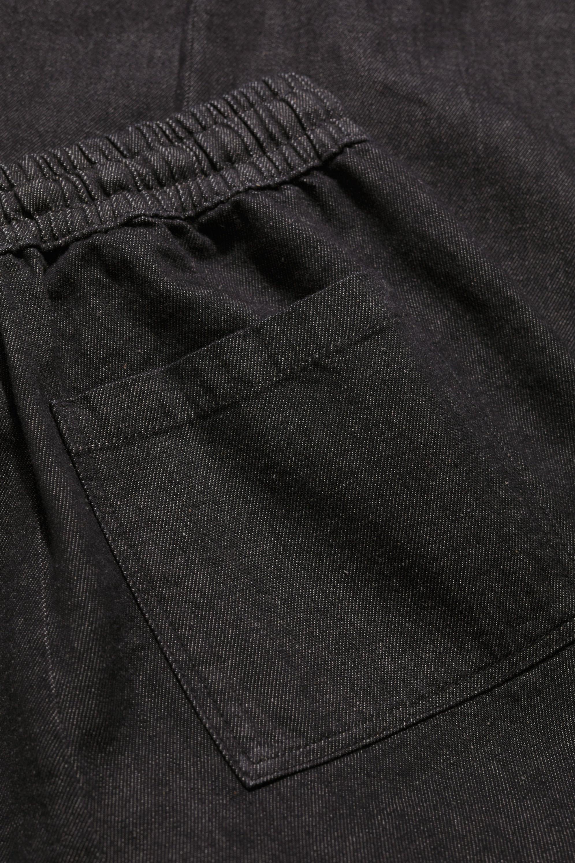 Close-up of a black organic cotton trouser pocket with an elasticated waistband.