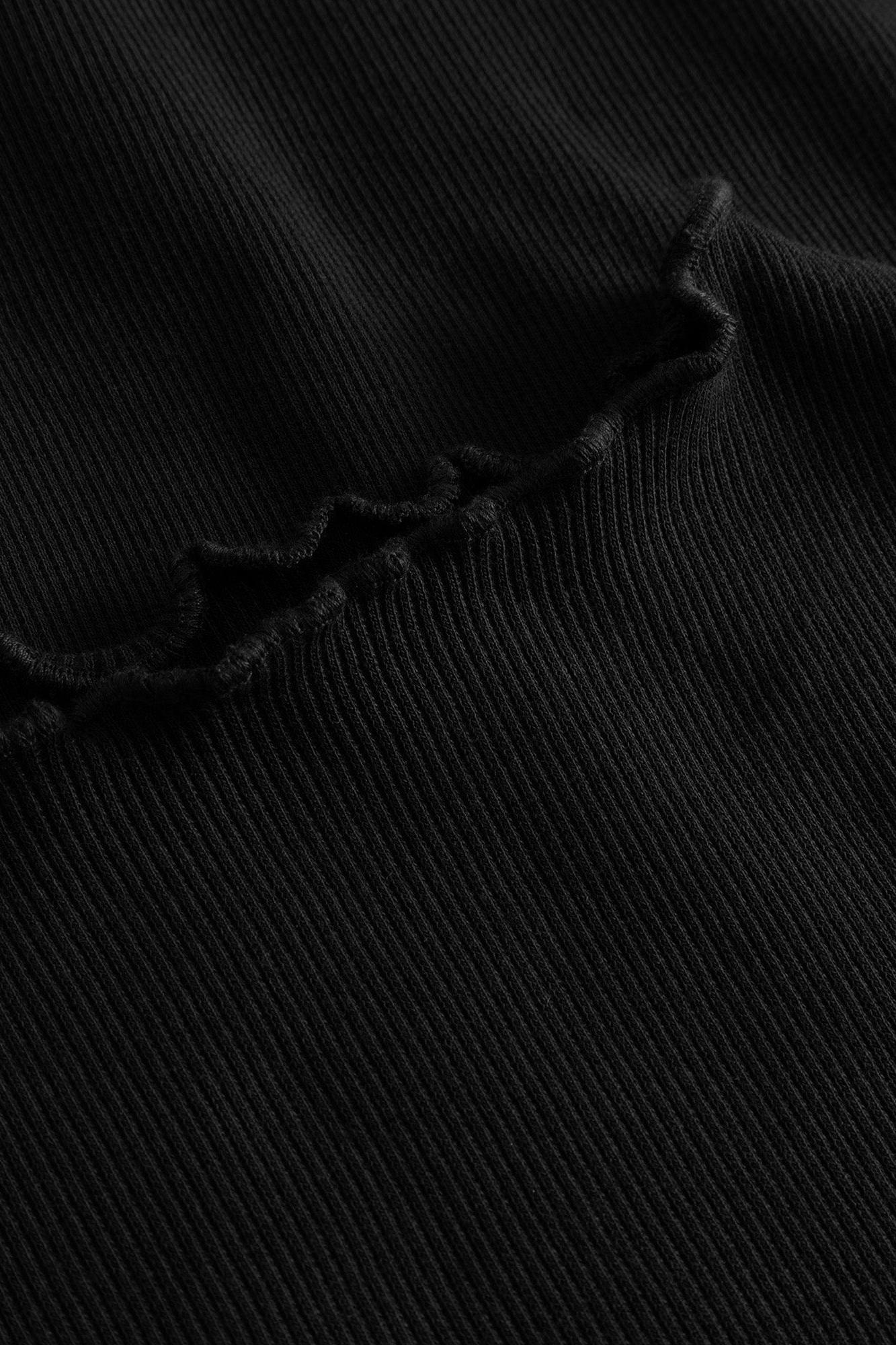 Close-up of a black ribbed knit fabric with a ruffled or scalloped edge detail.