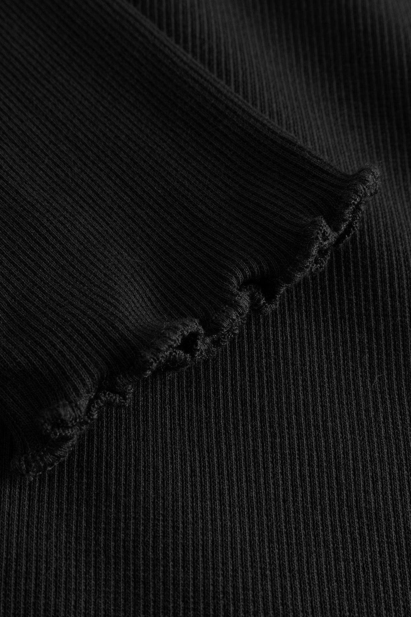 Close-up of a black ribbed knit fabric with a frayed, raw-edge hem detail.