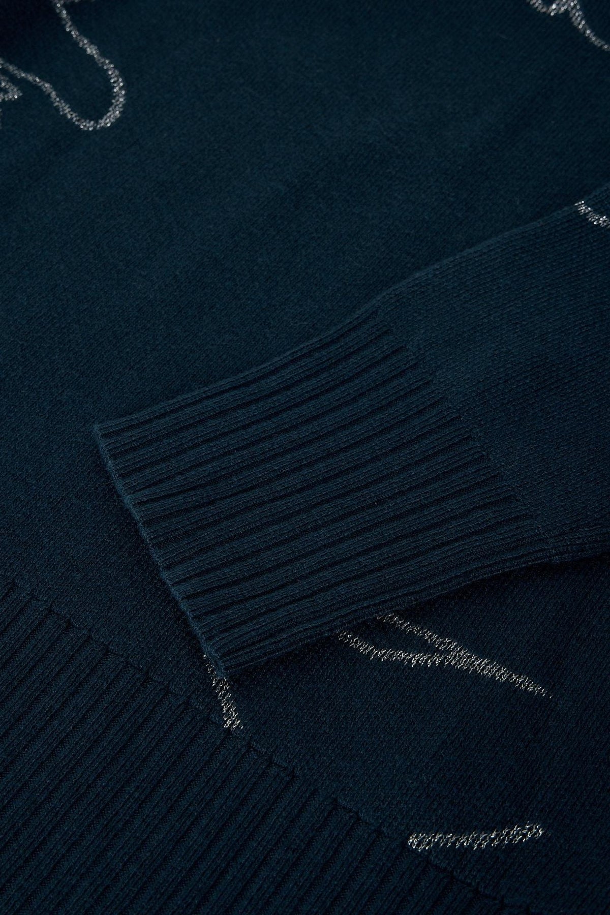 Close-up of a black women's jumper featuring a ribbed cuff and subtle sparkly silver metallic detailing.