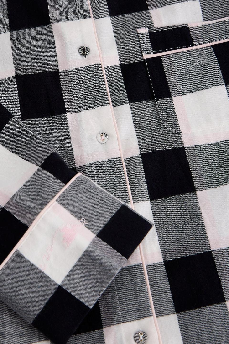 Close-up of a White Stuff black and white check organic cotton pyjama top with pink piping detail.