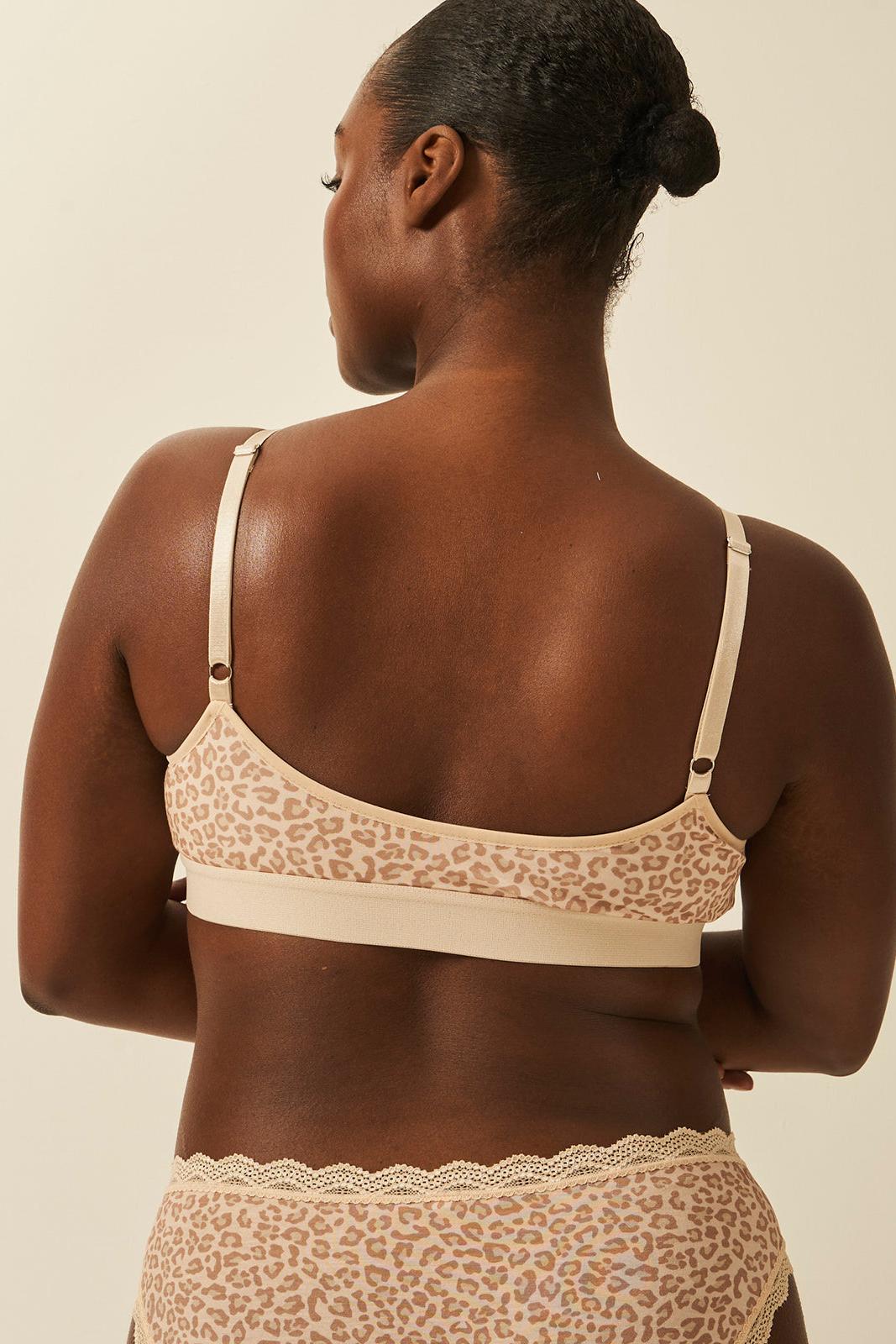 Woman wearing a beige leopard print bra and underwear set against a plain background