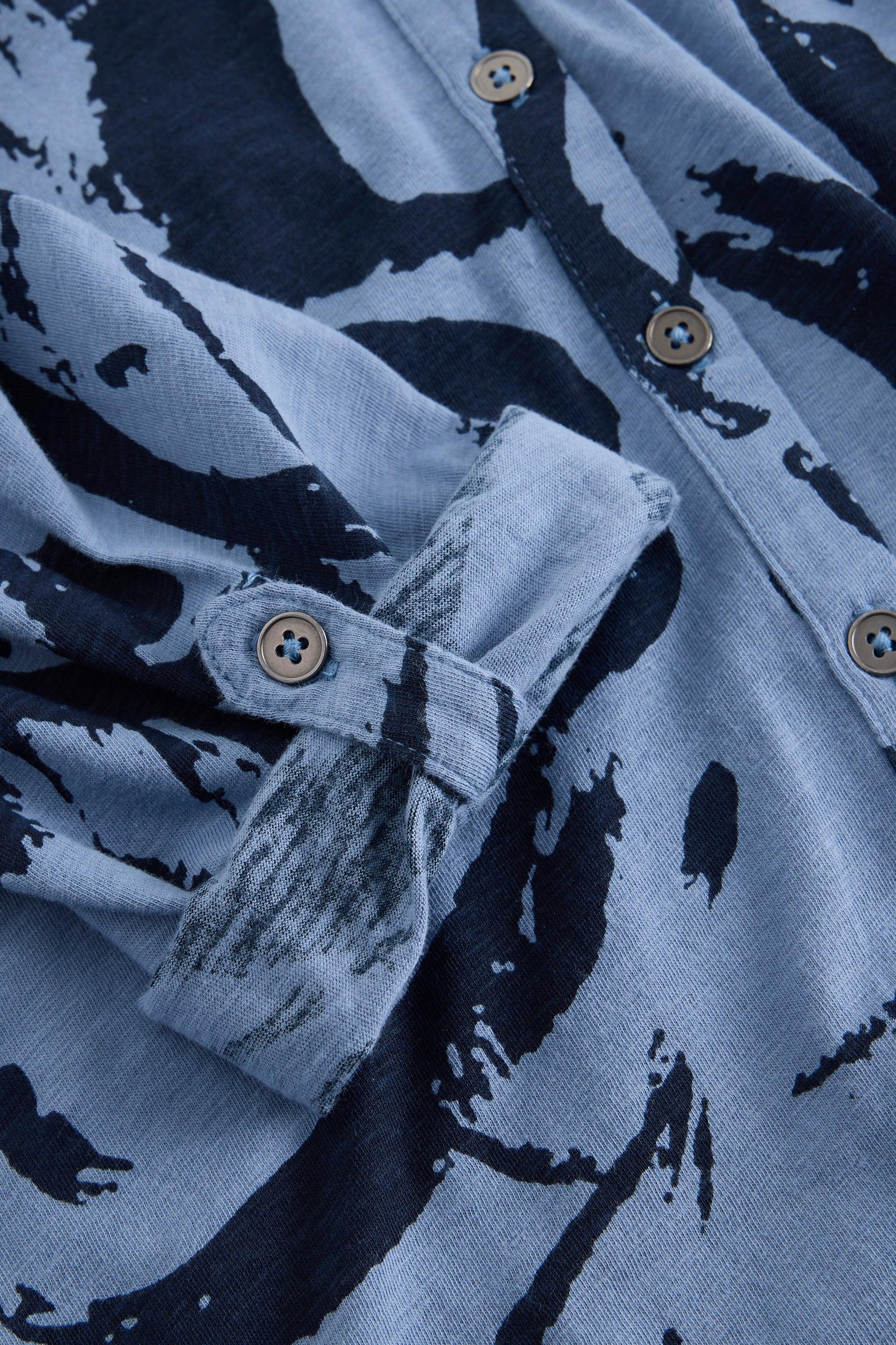 Close-up of a blue shirt with an abstract pattern and rolled-up sleeve showing cotton fabric texture