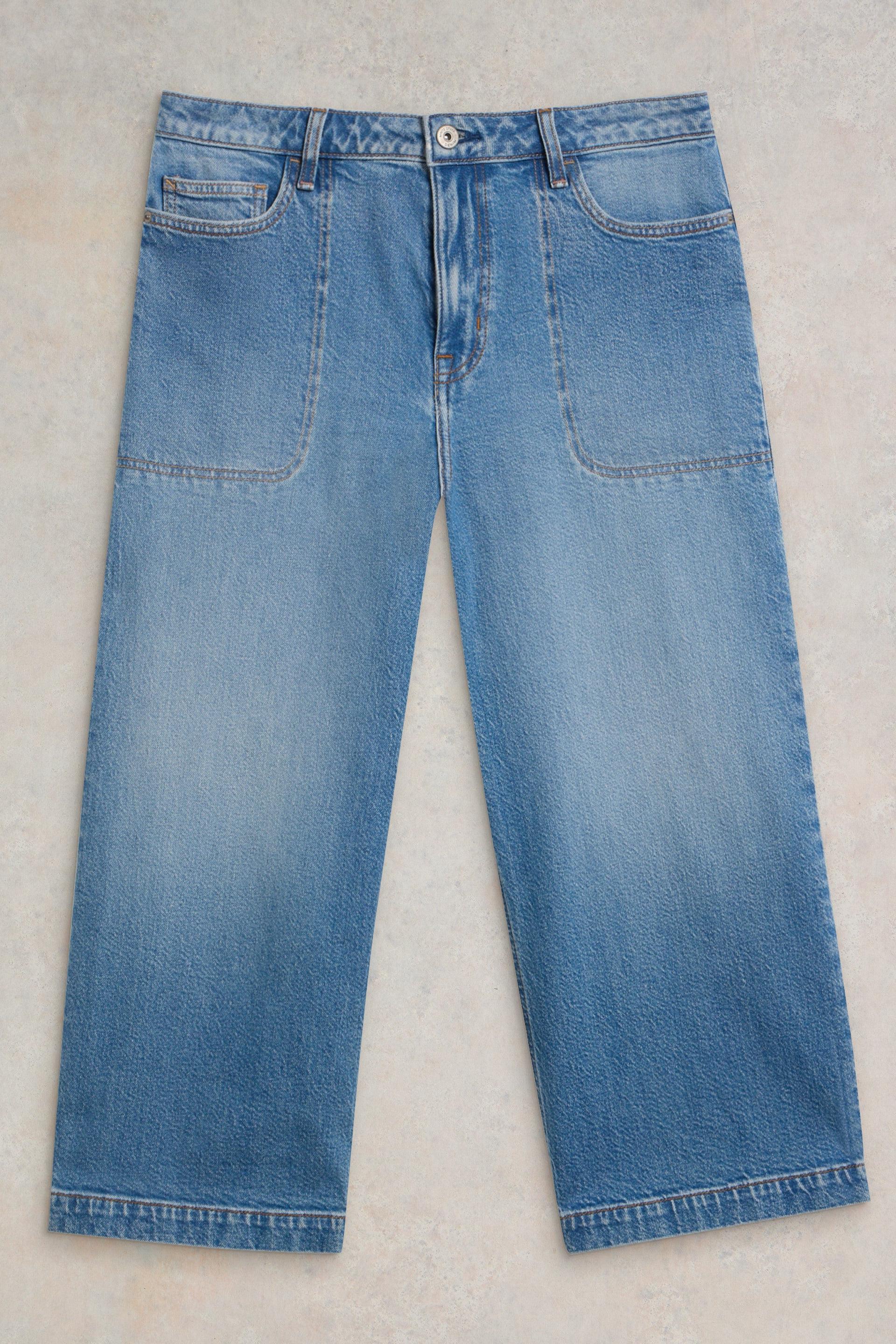 Wide-leg blue denim jeans made from organic cotton, laid flat on a light textured background