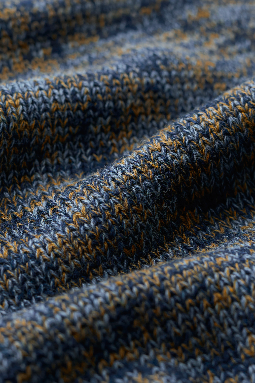 Close-up of a textured knit fabric with a marled pattern of navy blue, slate gray, and mustard yellow.