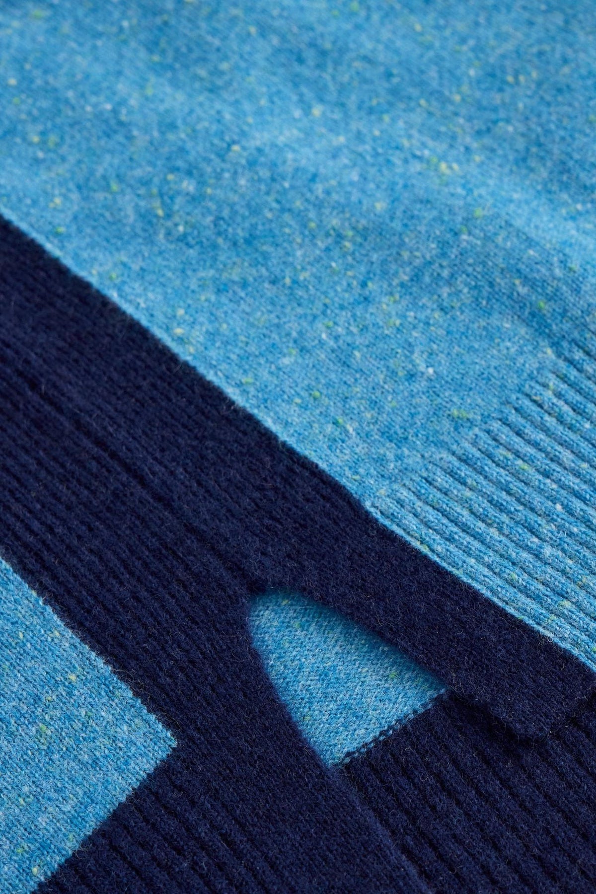 Close-up of a blue knit sweater showing detailed texture and ribbed pattern.