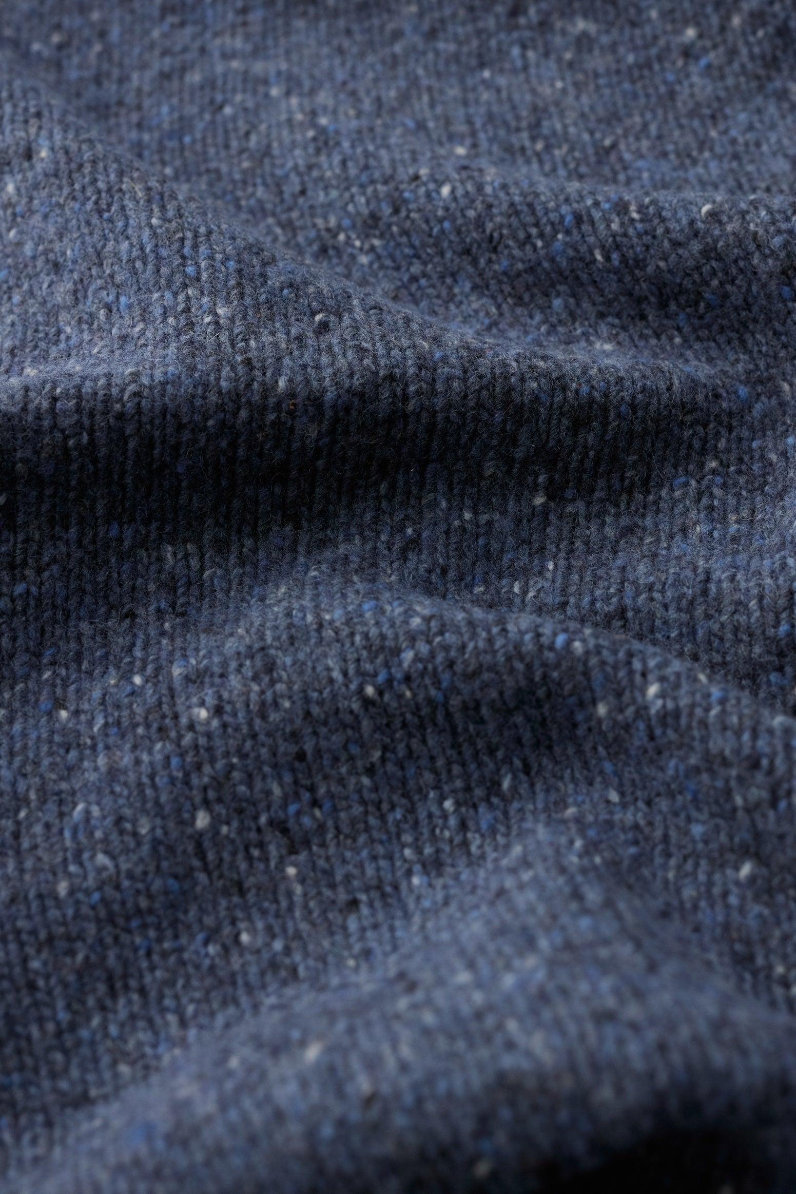 Close-up of a blue knit wool scarf with subtle flecked texture.
