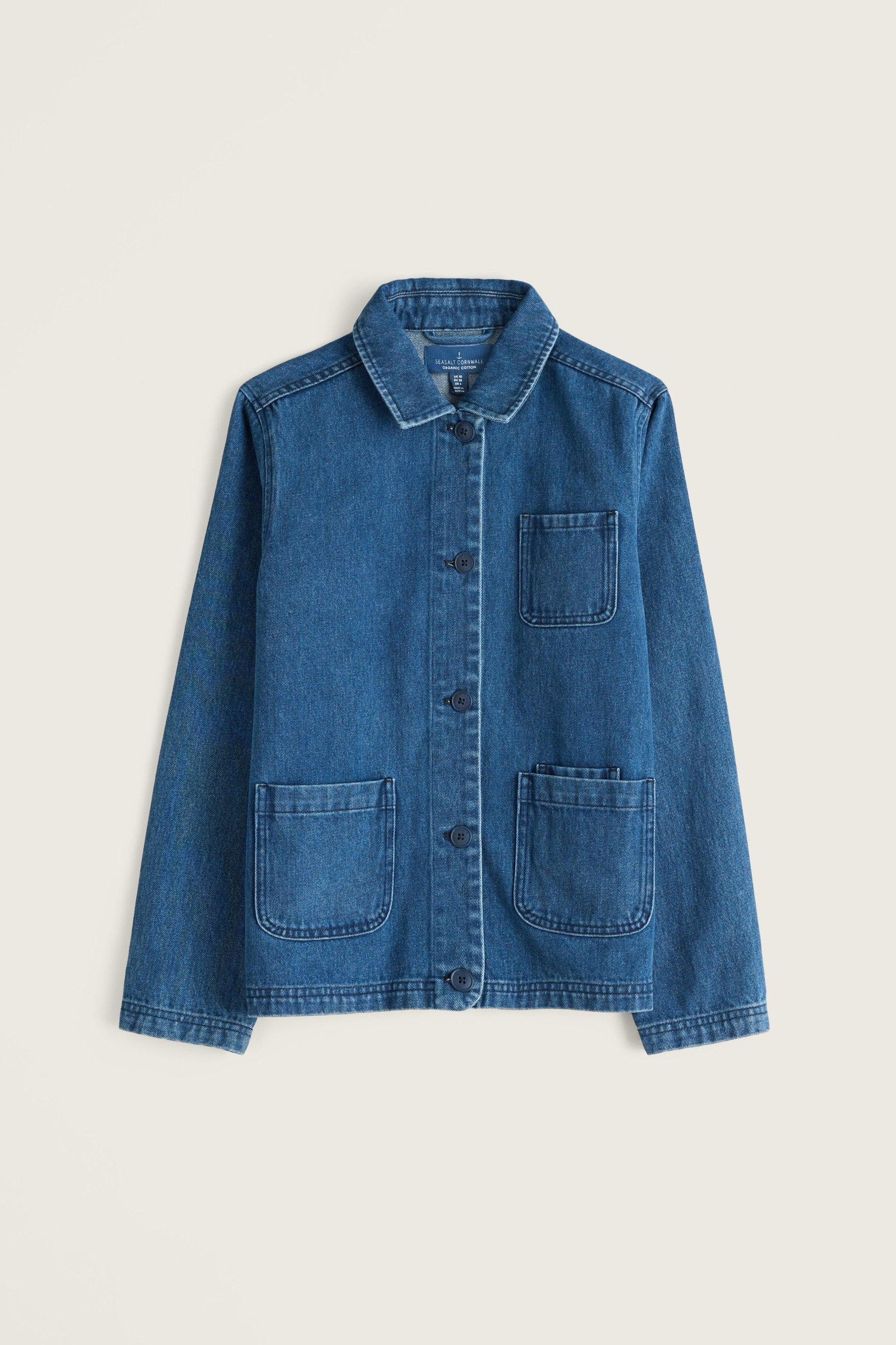 A blue denim utility jacket with a button-up front, pointed collar, and four front patch pockets, shown flat against a light beige background.
