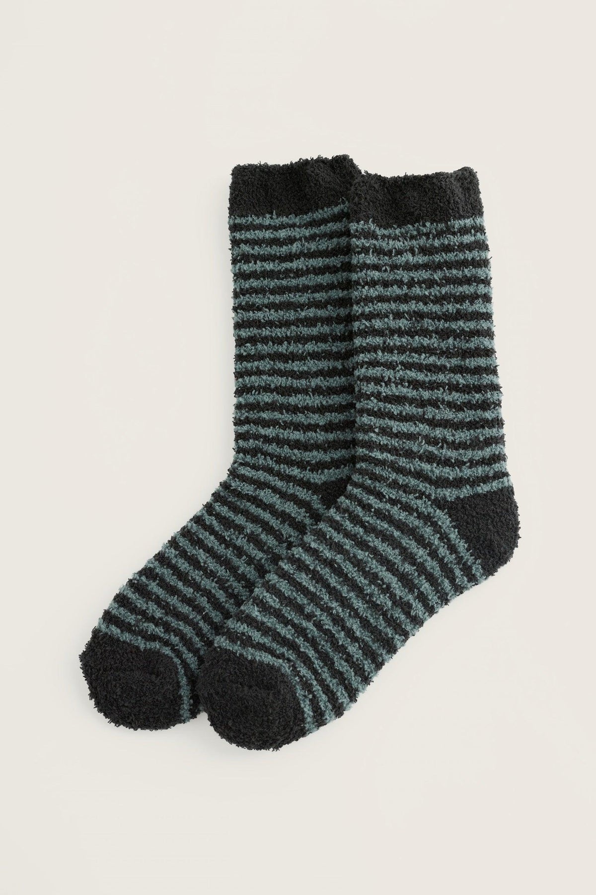 A pair of fluffy blue and black striped cosy socks on a neutral background.