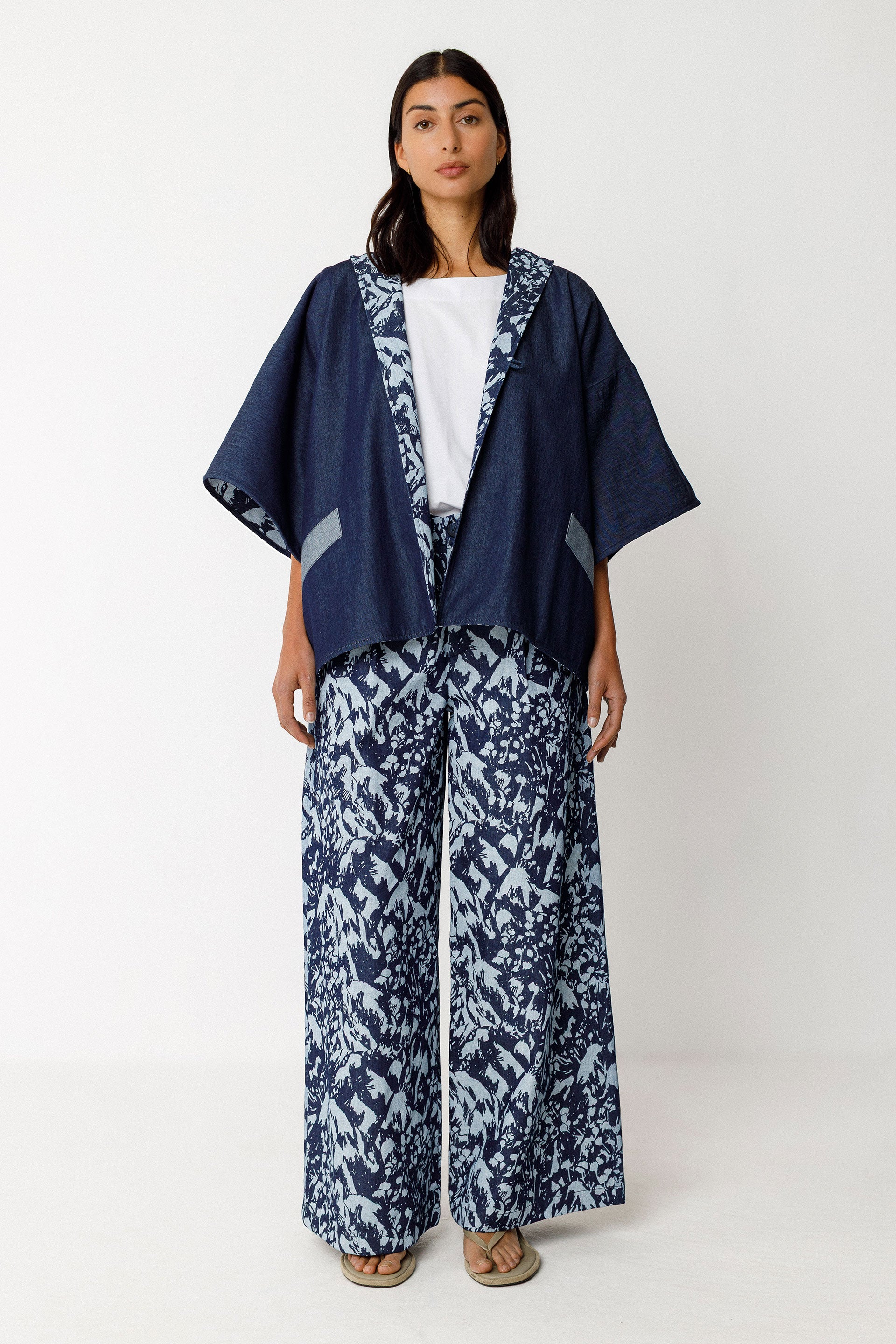 Woman wearing a navy kimono-style top and wide-leg organic cotton pants with white patterns on a white background