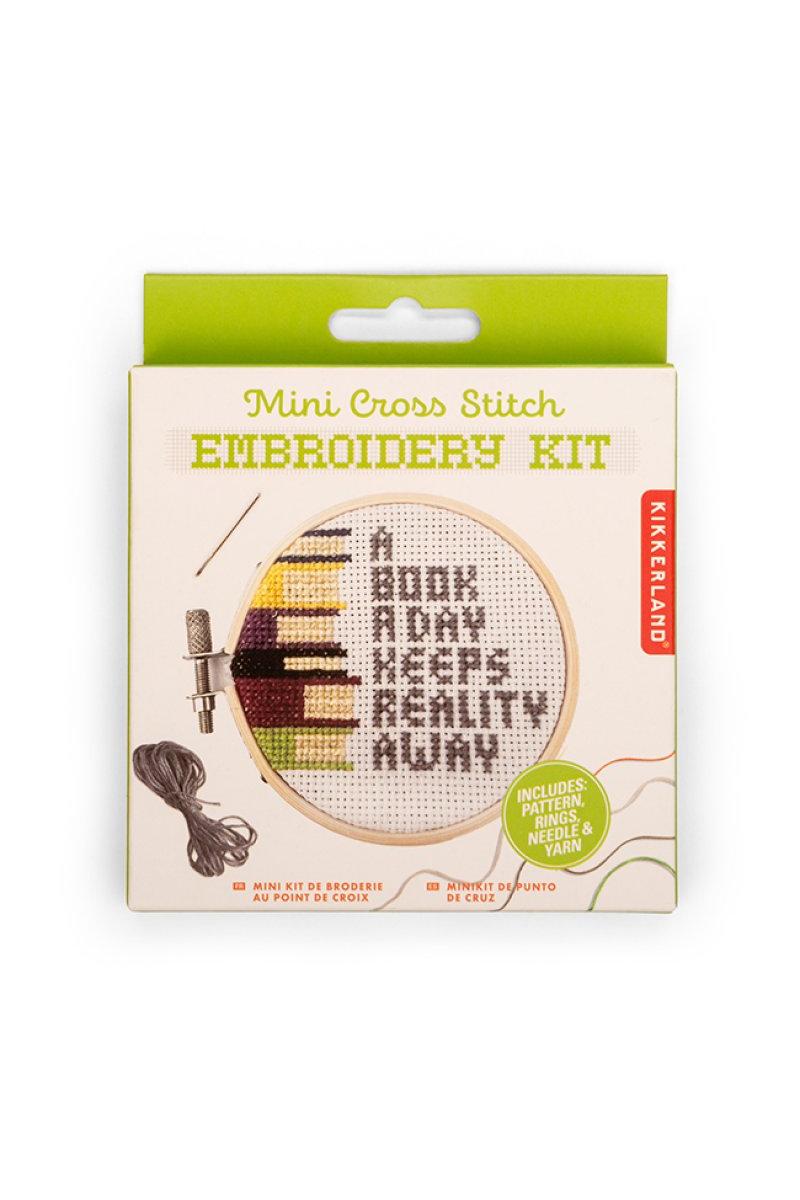 Kikkerland Mini Cross Stitch Embroidery Kit packaging with text 'A Book A Day Keeps Reality Away'.
