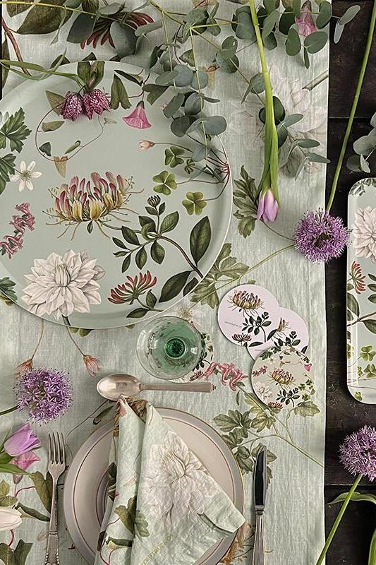 Floral table setting with plates, cutlery, and greenery on a wooden surface.