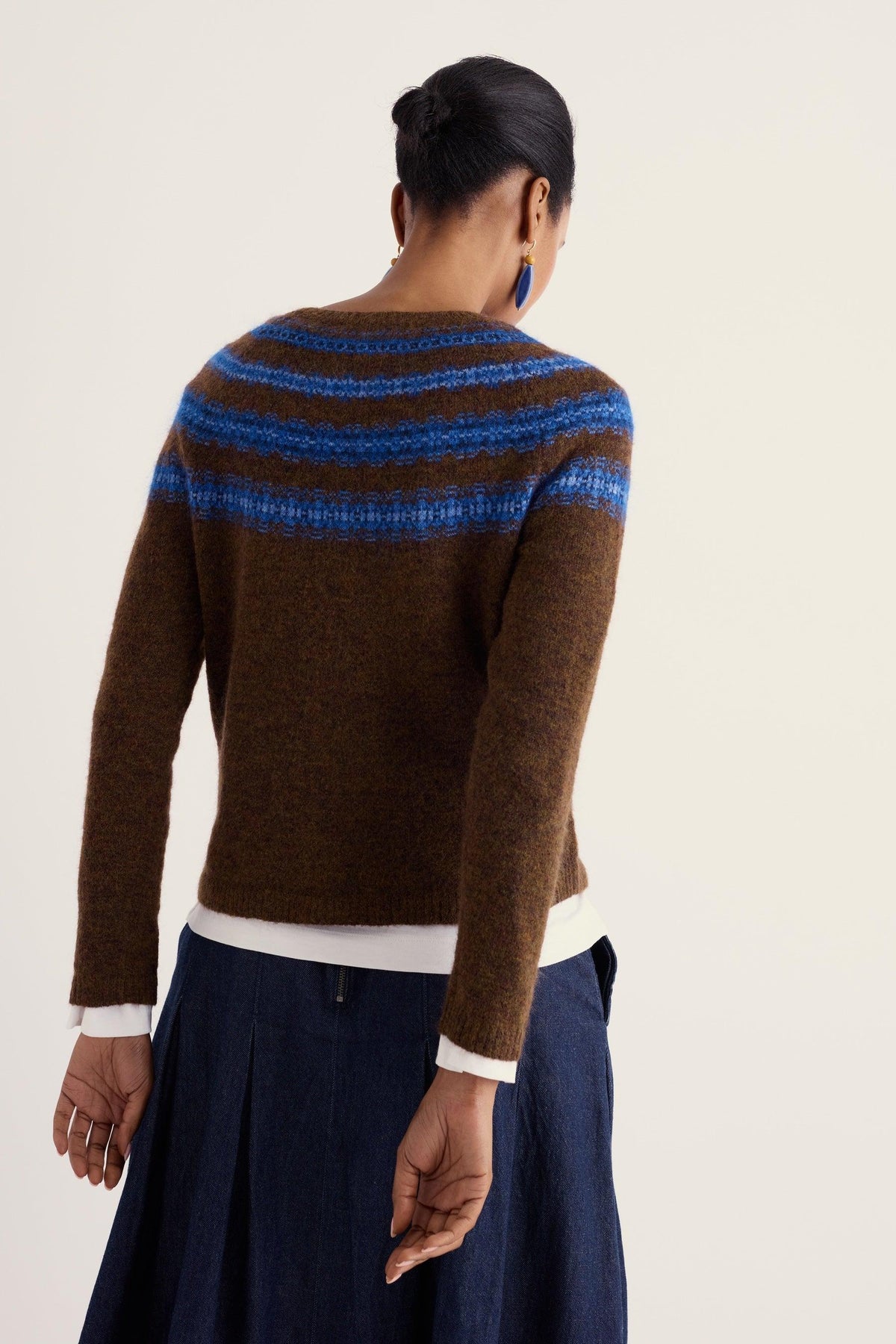 Woman seen from behind wearing a brown Fairisle wool jumper by Seasalt Cornwall over a dark blue skirt.