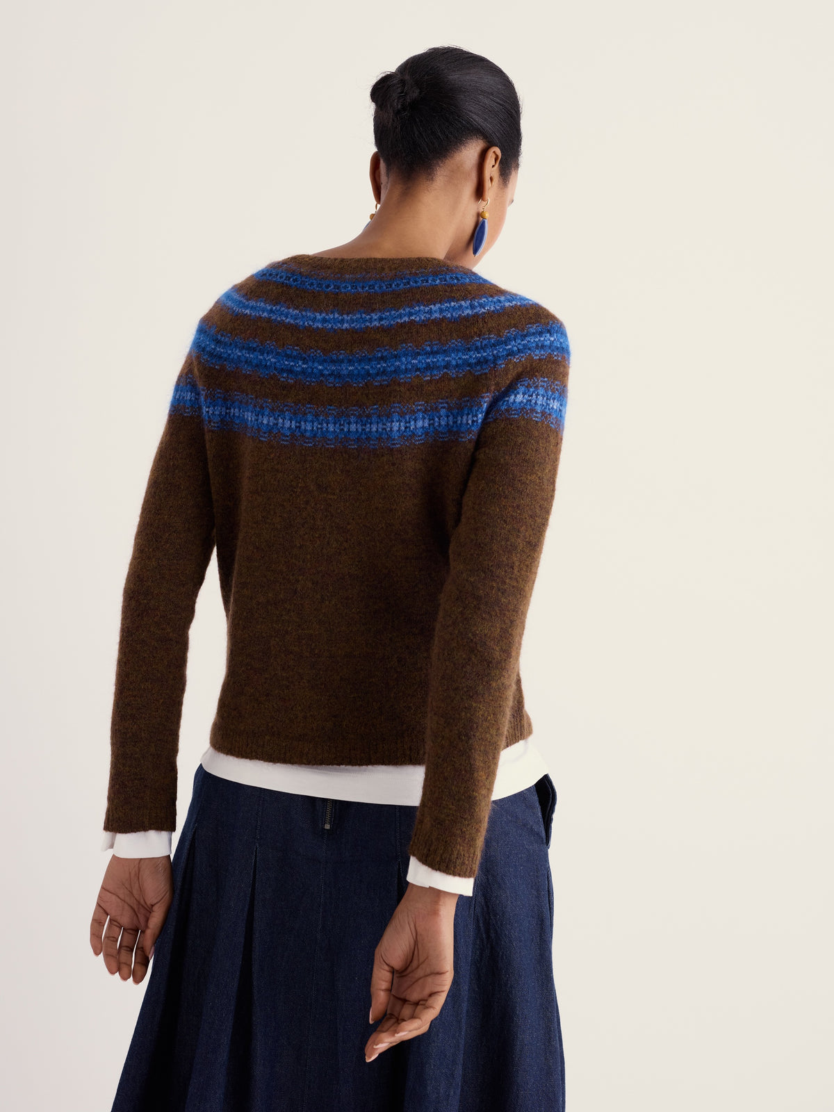 Woman seen from behind wearing a brown Fairisle wool jumper by Seasalt Cornwall over a dark blue skirt.