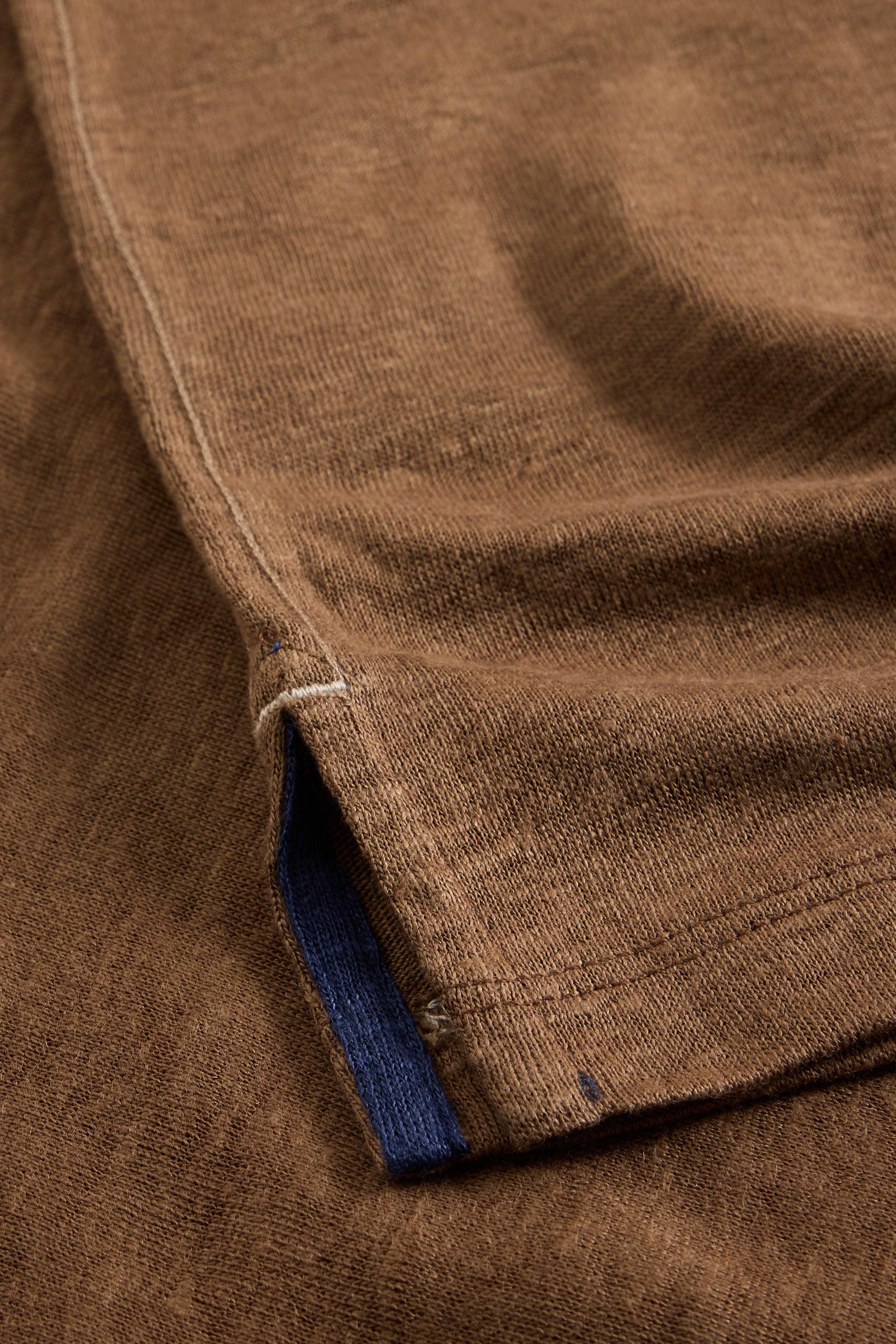 Close-up of a brown sustainable mens linen t-shirt highlighting the fabric texture and hem detail.