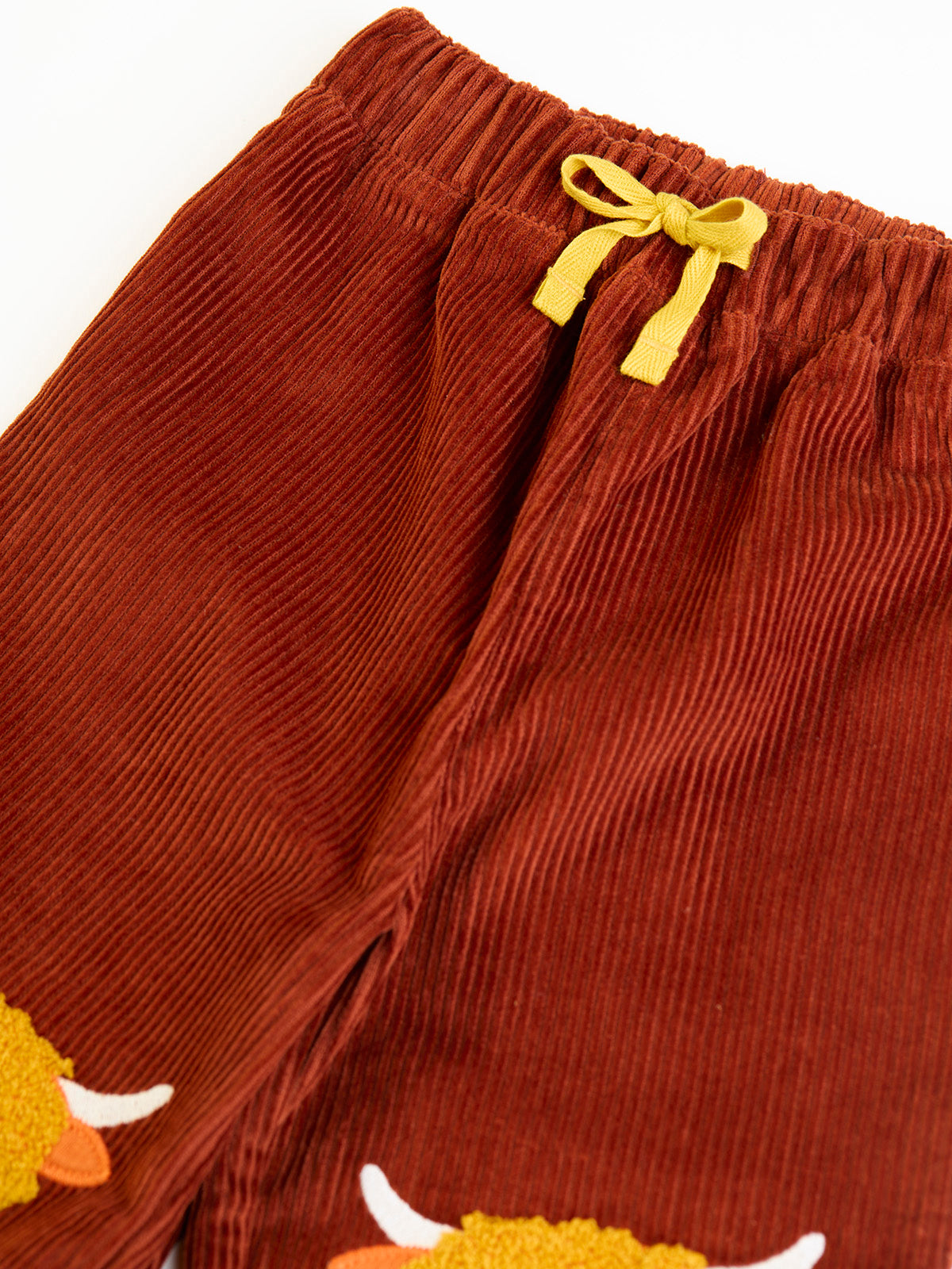 Brown organic cotton corduroy trousers for boys featuring a cute highland cow embroidery detail.