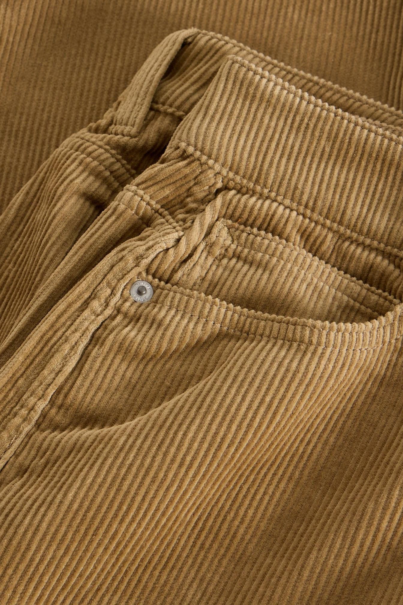 Close-up of tan corduroy women's trousers with White Stuff branded metal rivet.