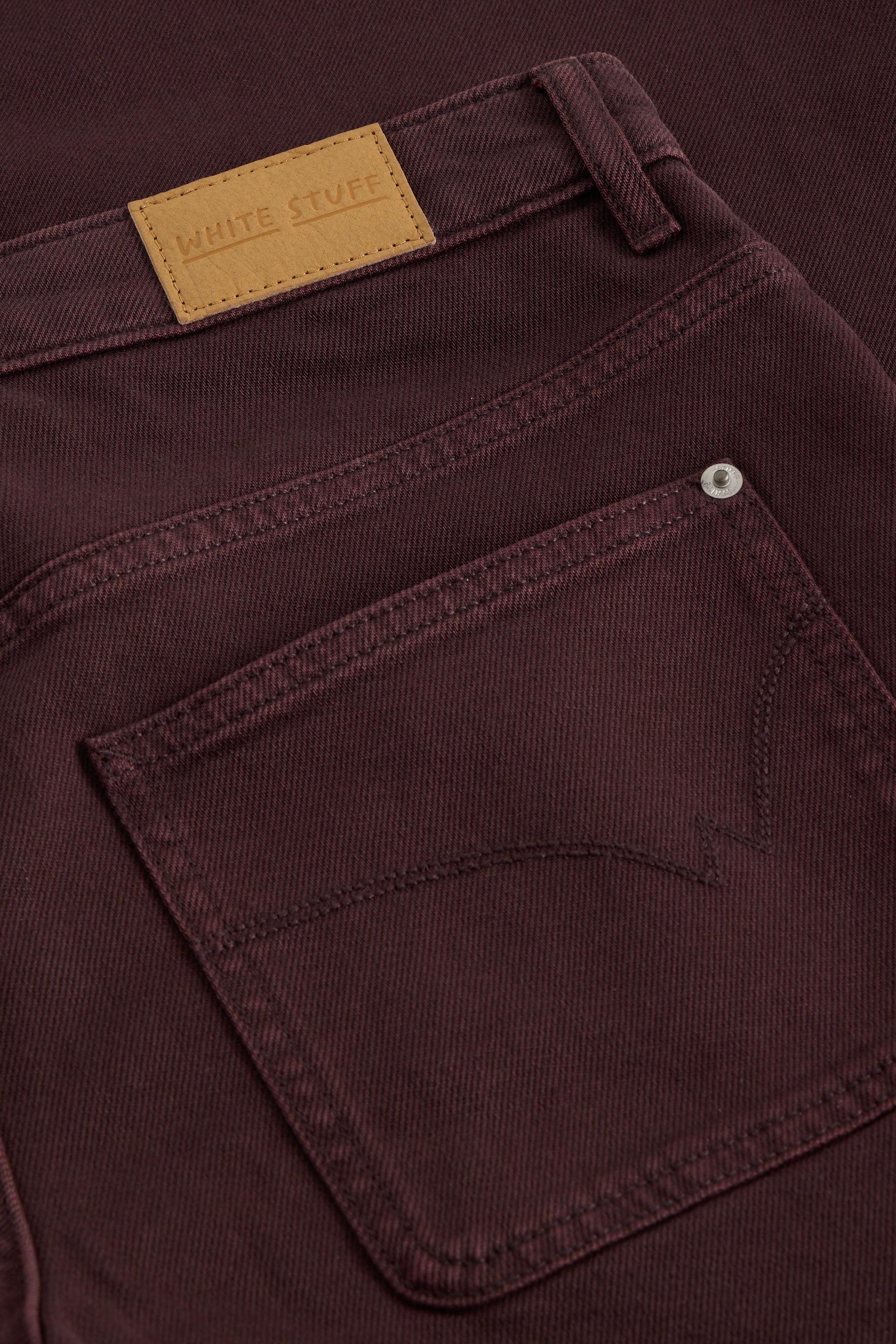 Close-up of burgundy White Stuff jeans pocket with branded leather patch and metal rivet