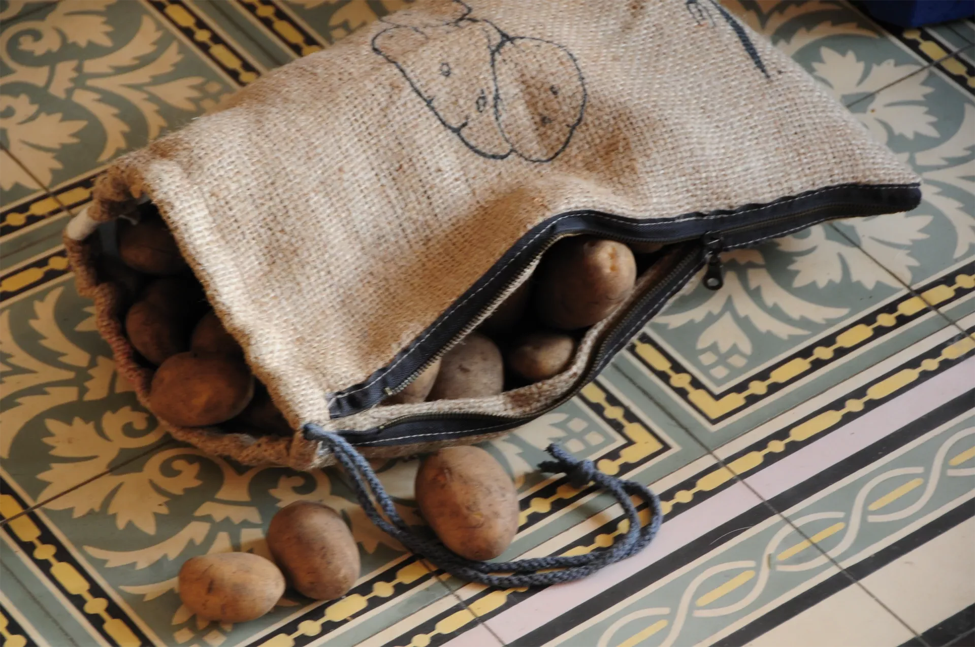 Hessian bag with potatoes on a patterned floor