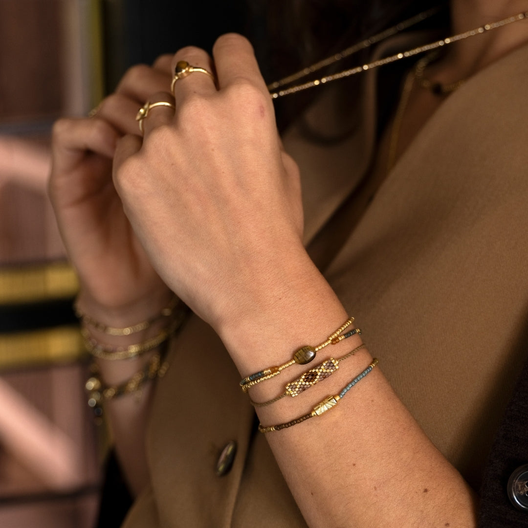 A stack of delicate bracelets with a carnelian gemstone on a woman's wrist, perfect as a sustainable gift for her.