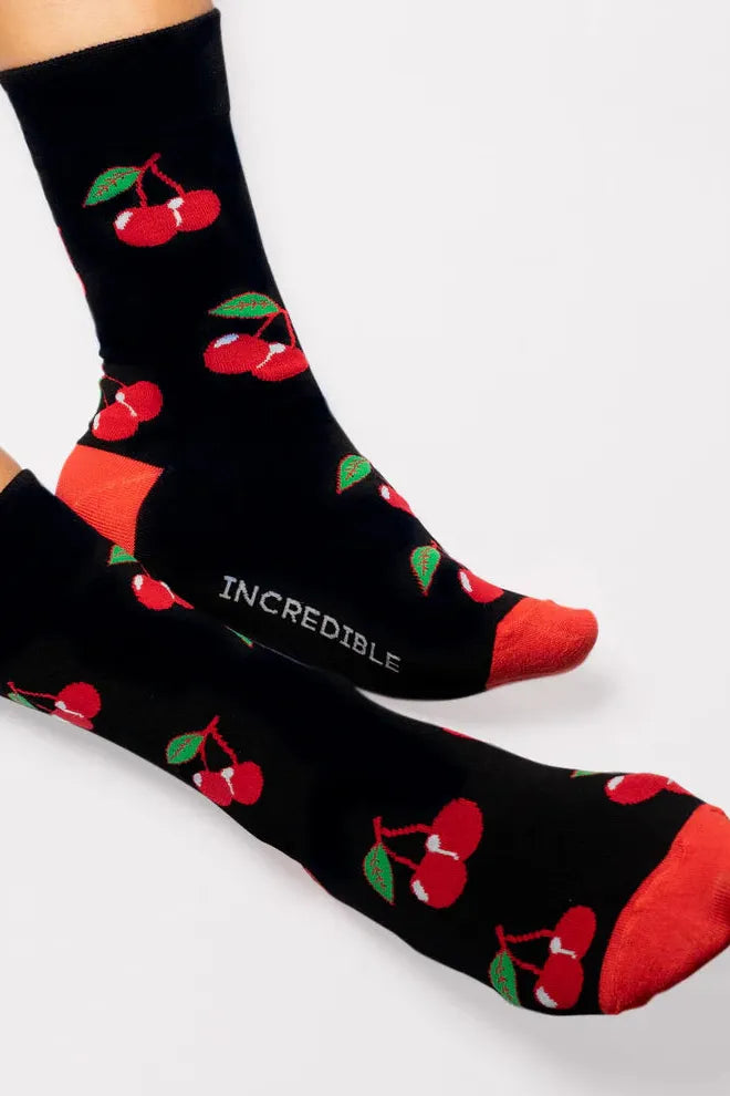 A pair of black bamboo socks featuring a red cherry pattern on a white background