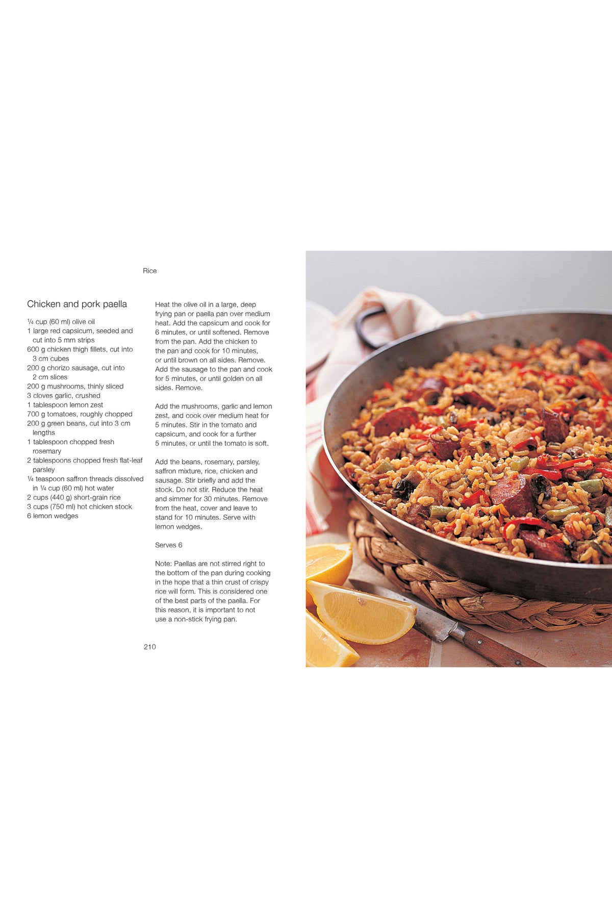 A cookbook page featuring a photo of chicken and pork paella in a frying pan with lemon wedges.
