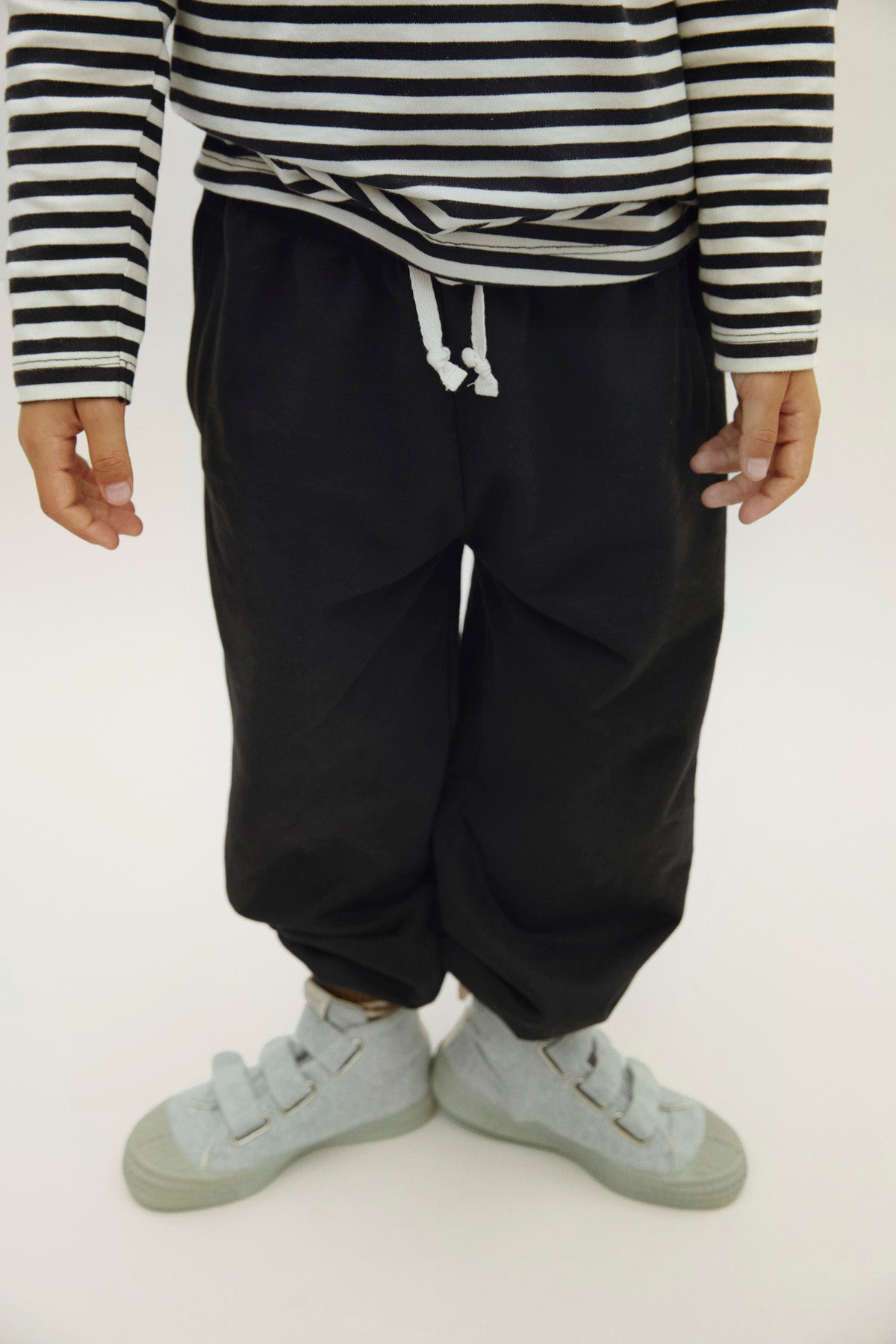 Person wearing a striped shirt and black pants on a white background