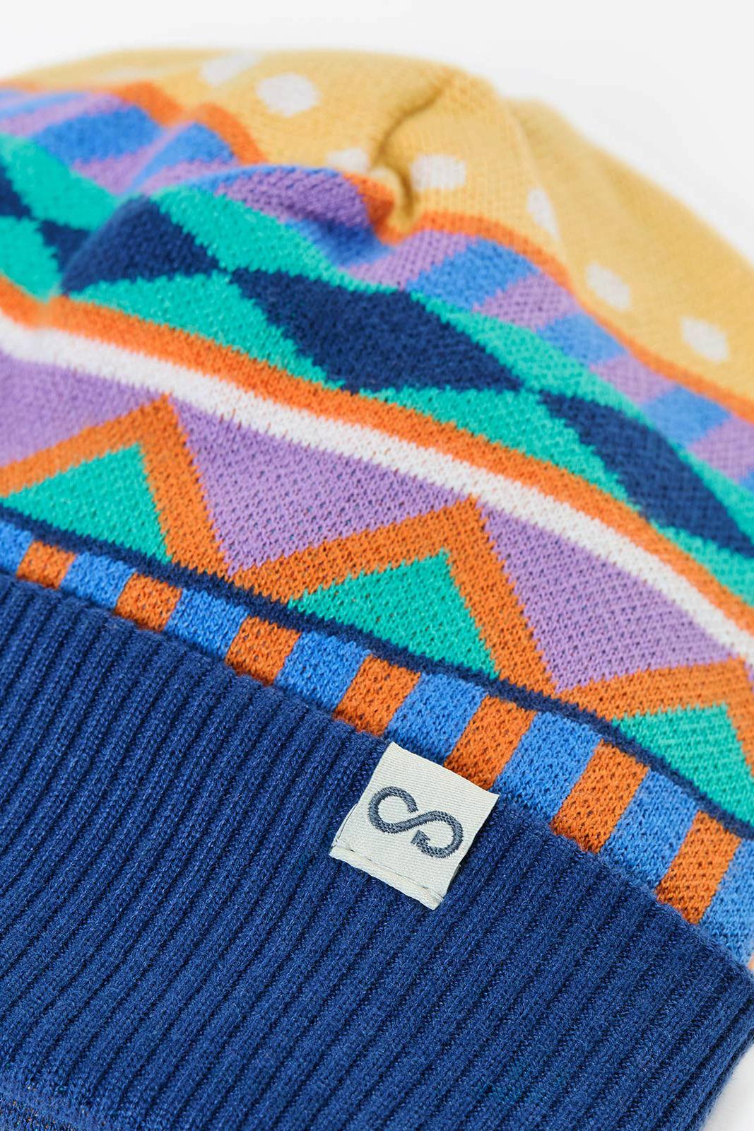 A colorful Frugi beanie hat featuring a geometric pattern and a solid dark blue ribbed cuff