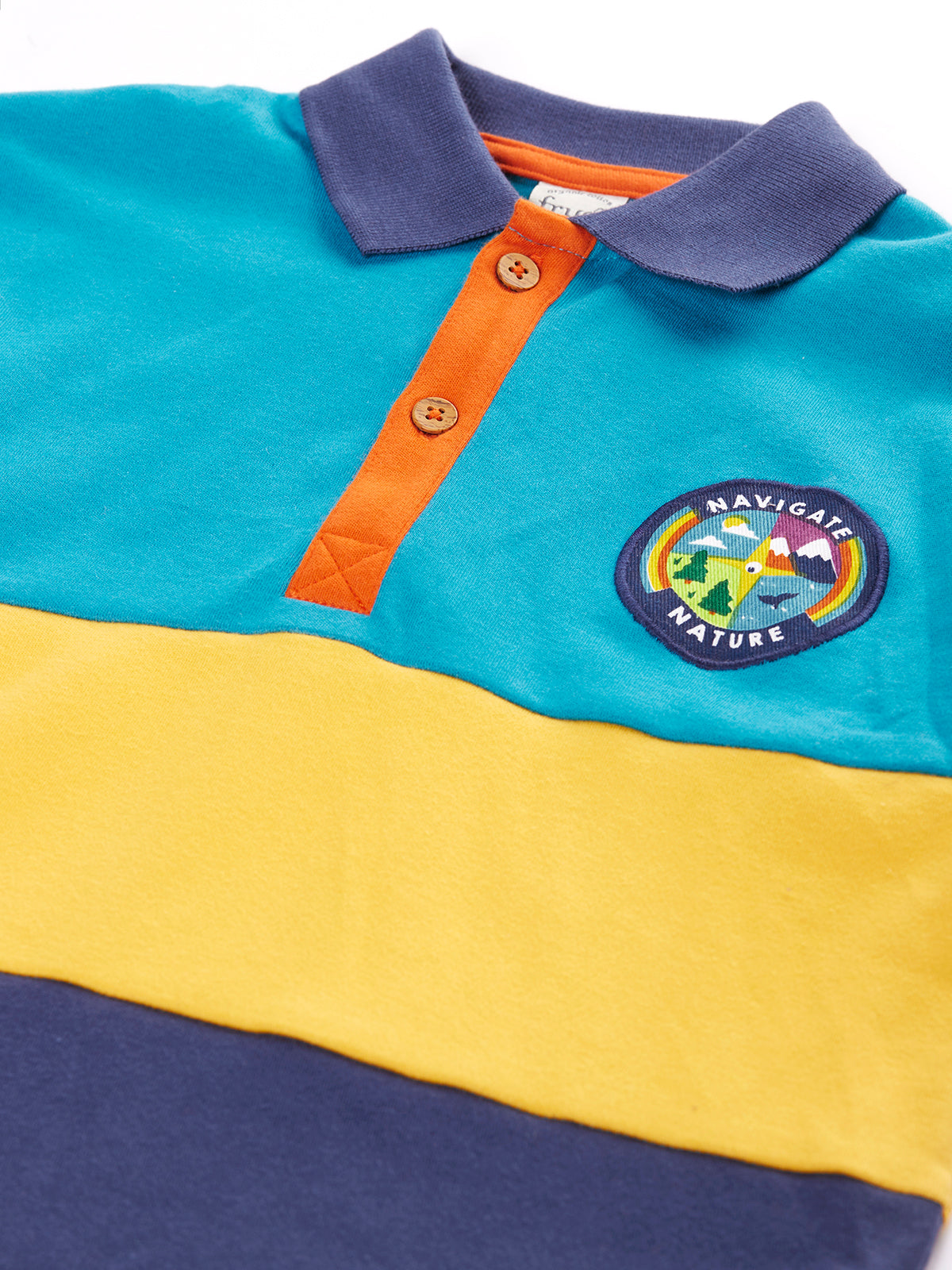 Close up of a colourful Frugi organic cotton rugby shirt with a nature-themed patch.