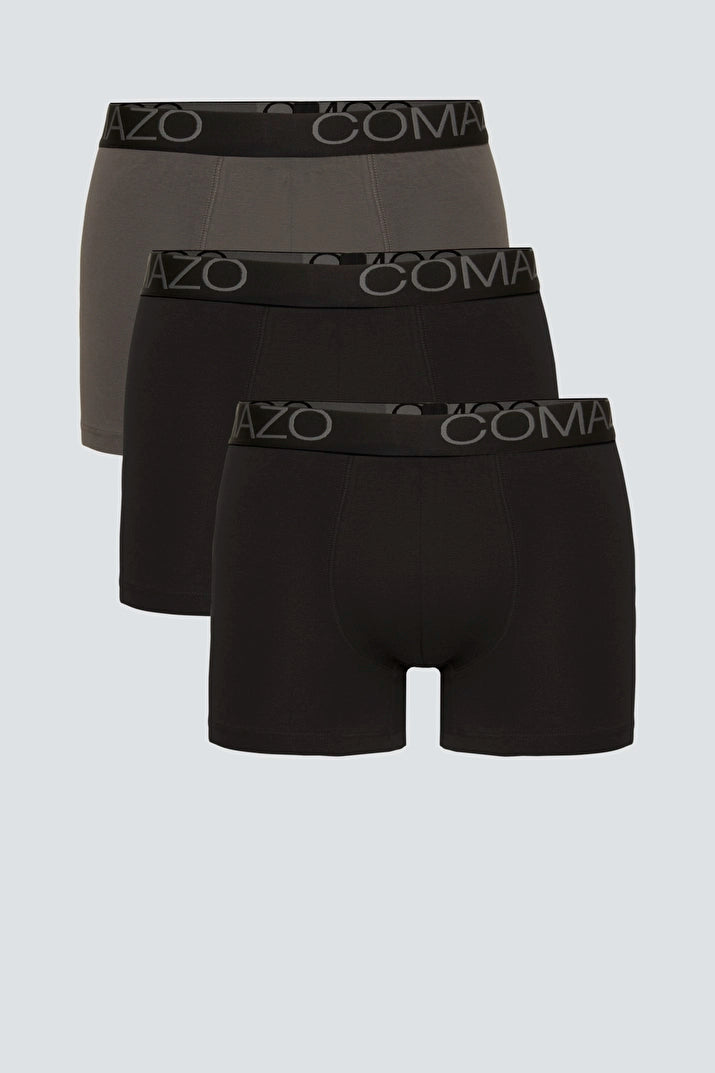 Stack of three Comazo men’s boxer briefs made from organic cotton in black and grey colors.
