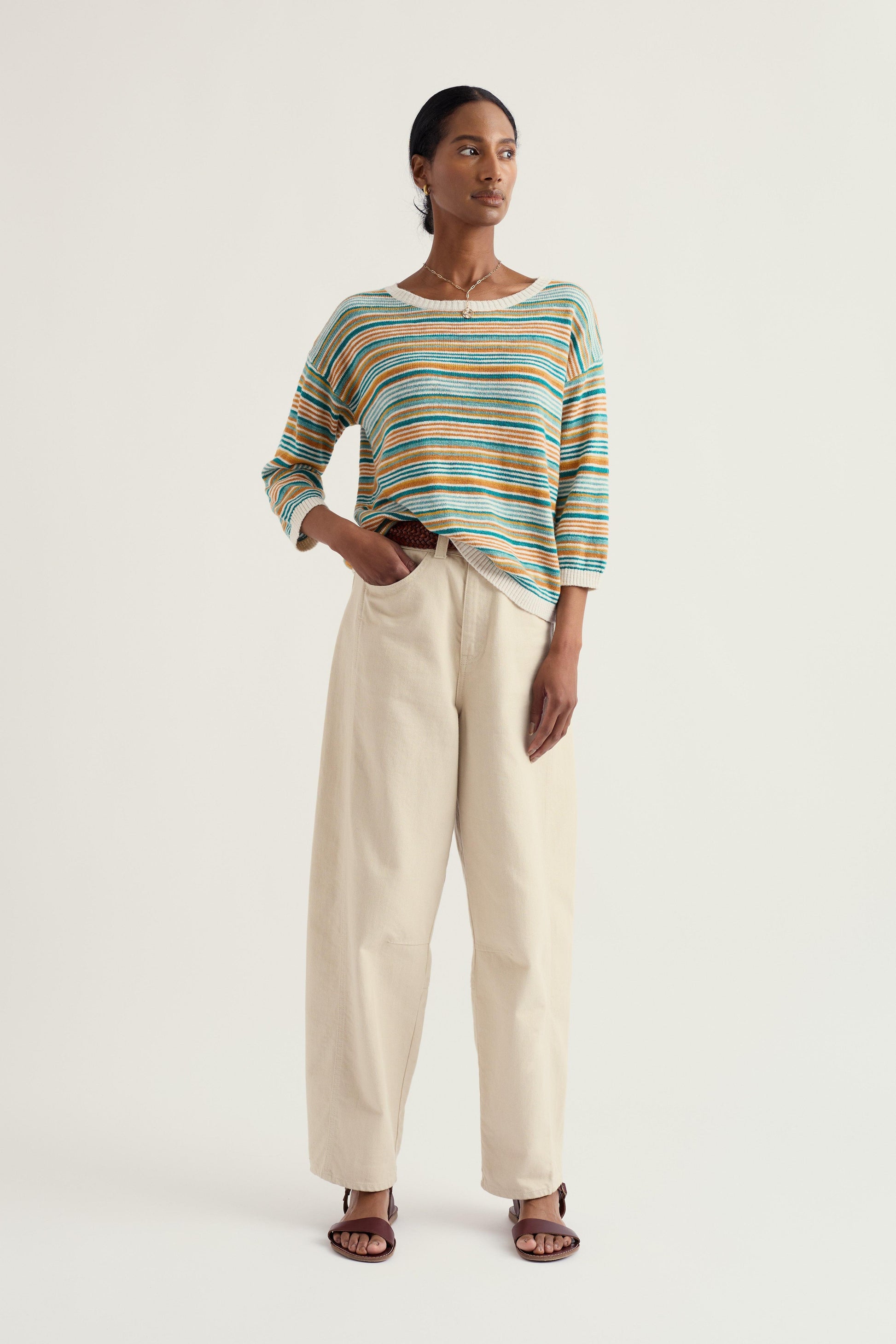 Woman wearing a striped sweater and beige pants on a white background