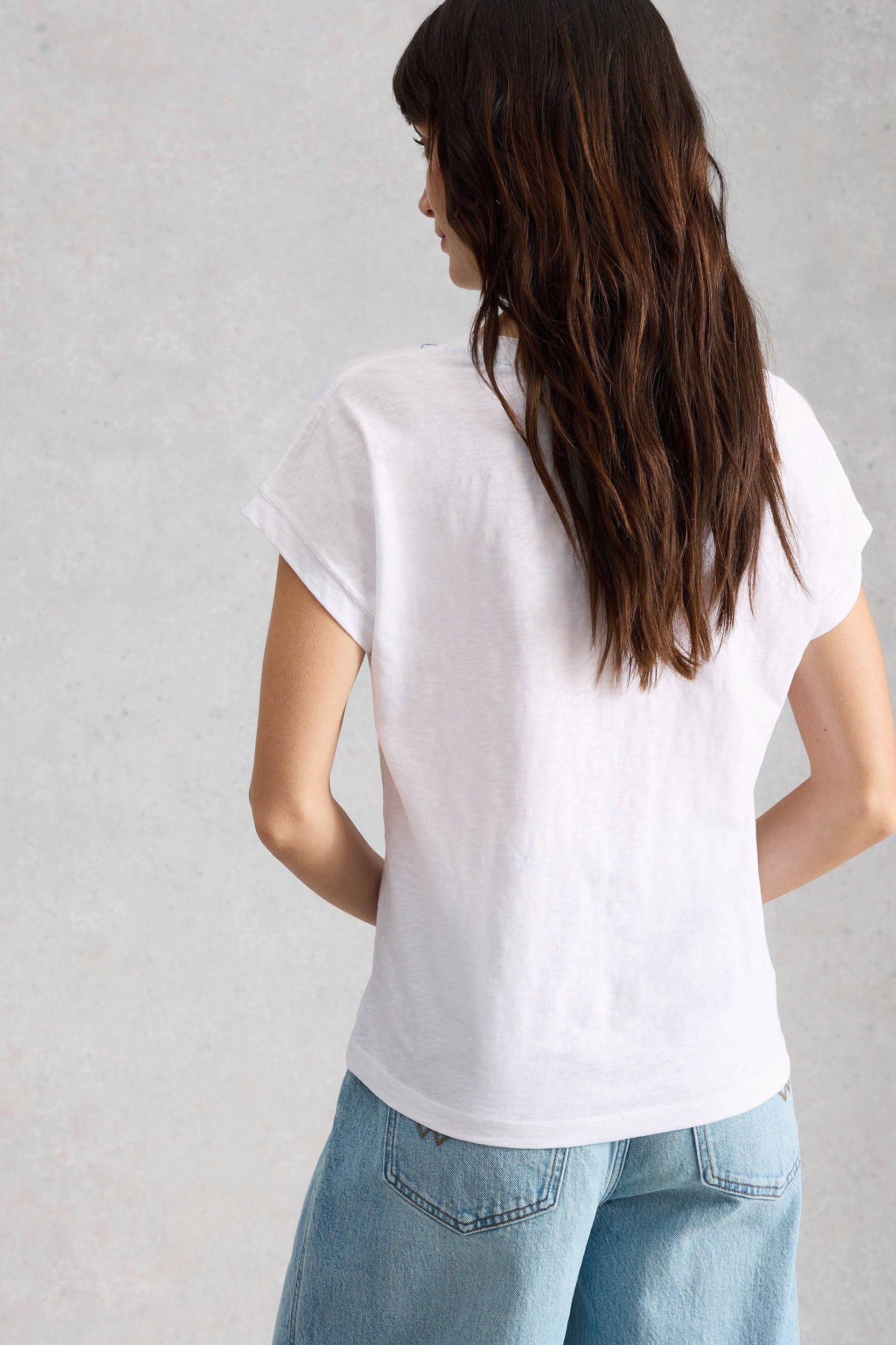 Person wearing a plain white t-shirt and light blue jeans against a gray background