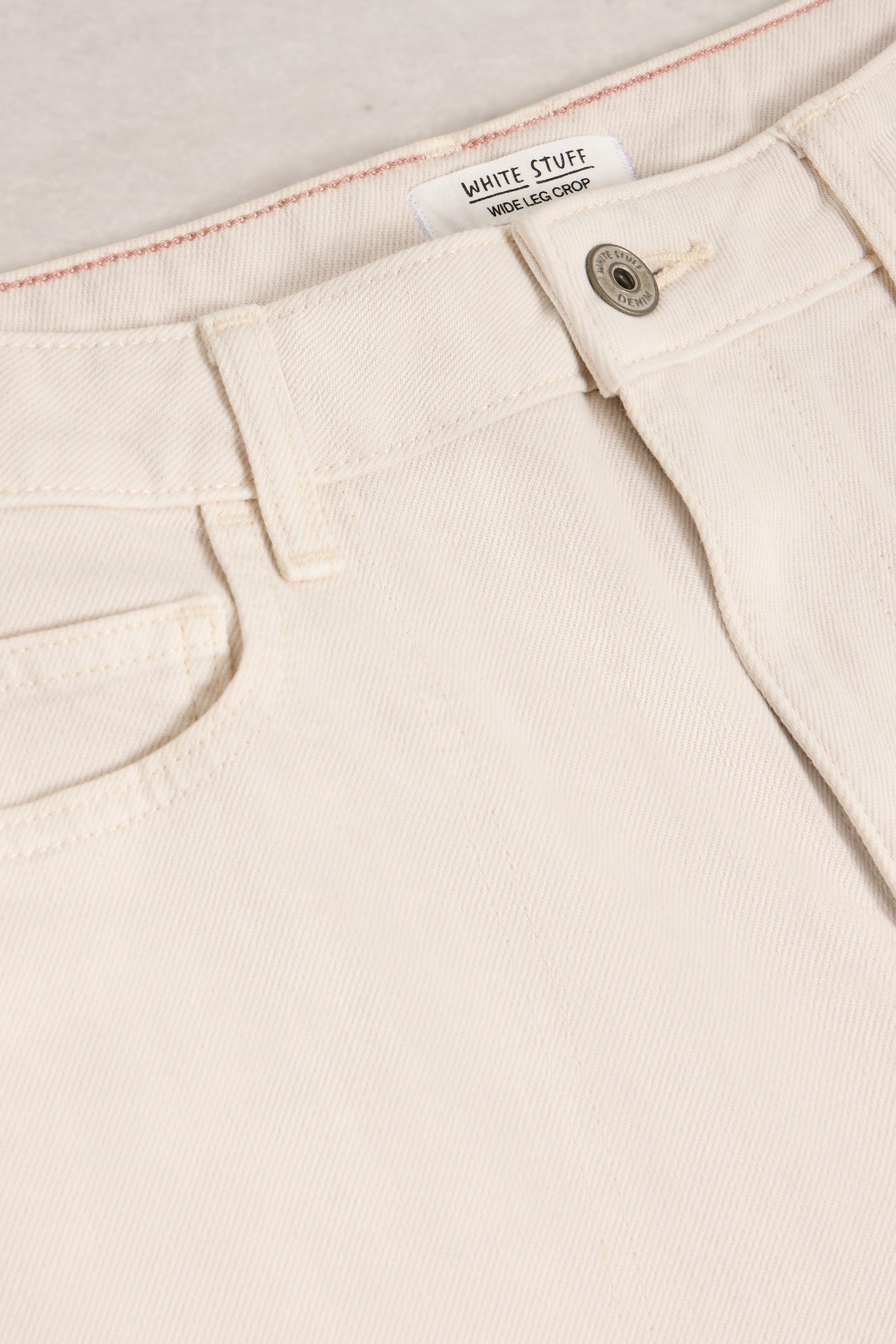 Close-up of beige pants with a button and label on a light background