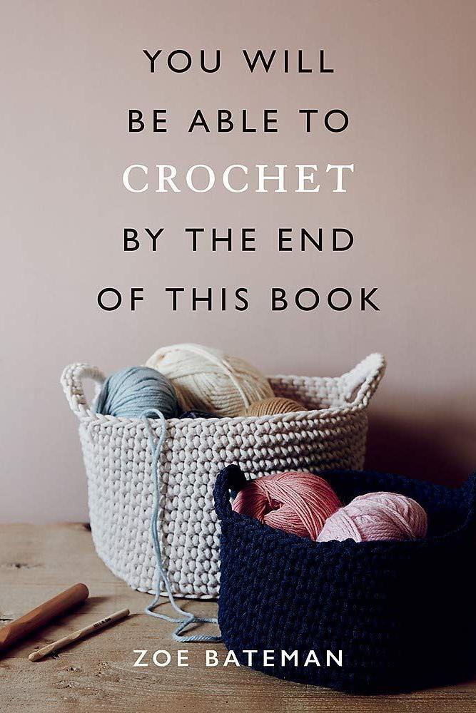 Book cover with yarn and crochet hooks on a wooden surface, featuring text about learning to crochet.