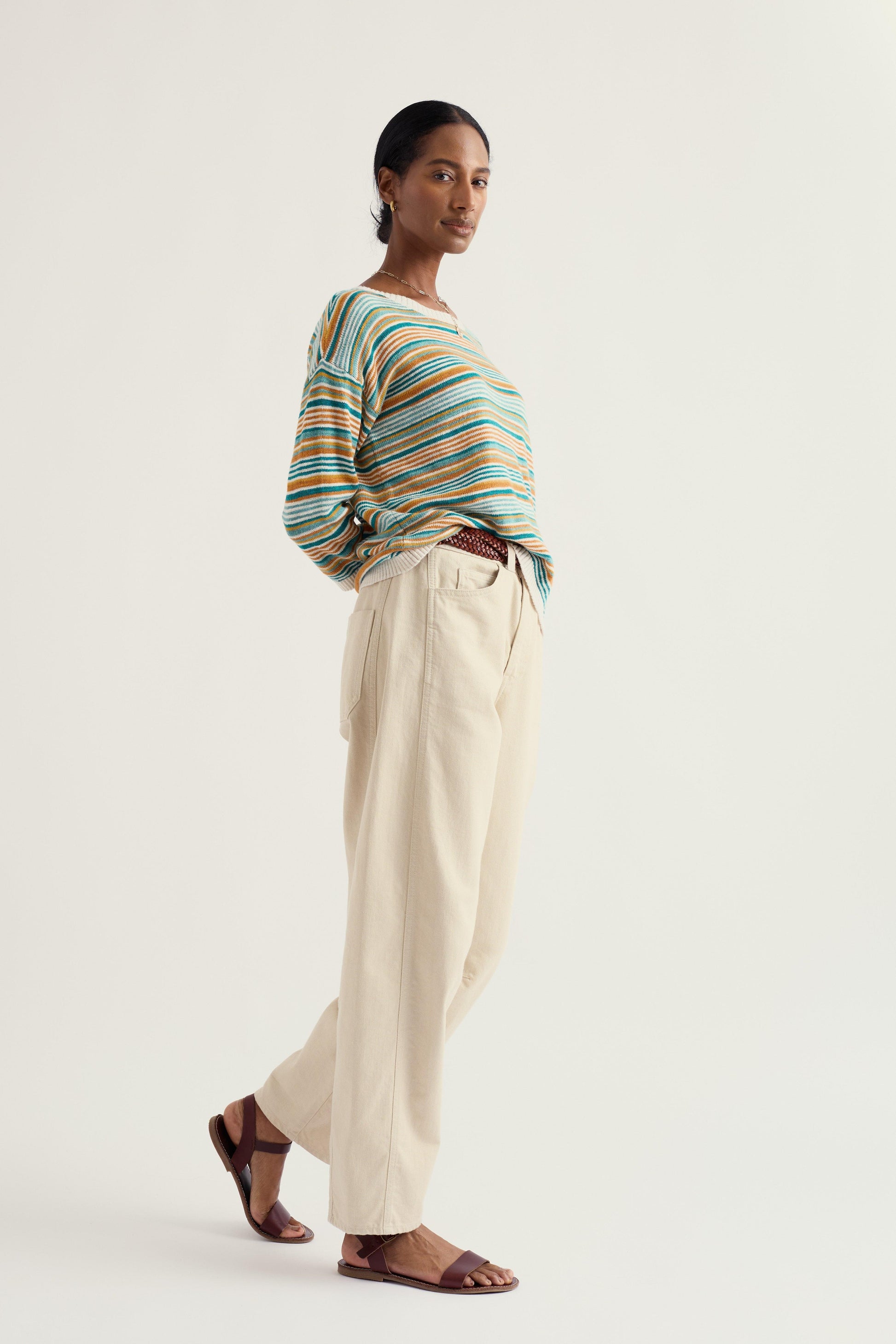 Woman wearing a striped relaxed fit sweater and beige pants on a white background