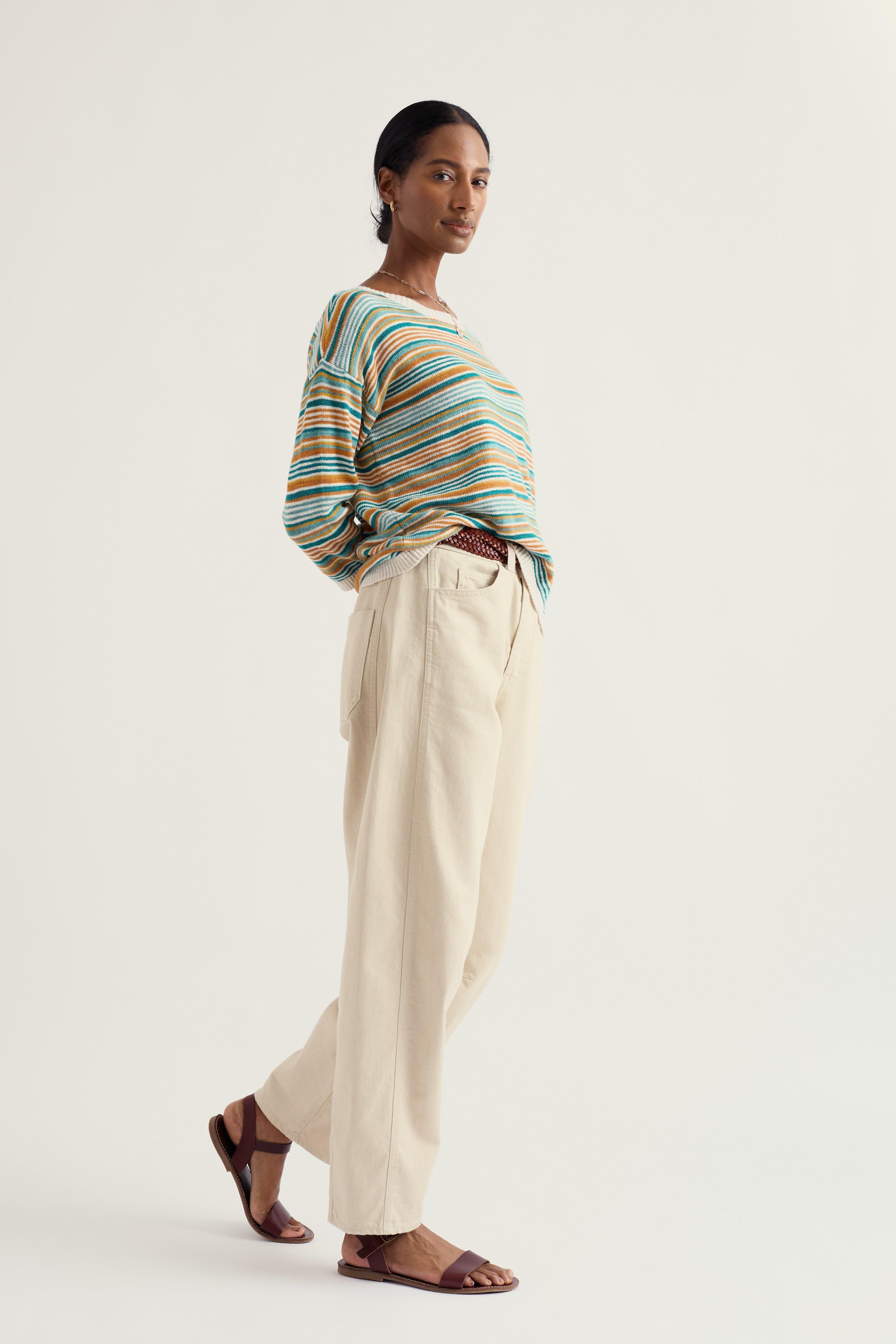 Woman wearing a striped relaxed fit sweater and beige pants on a white background