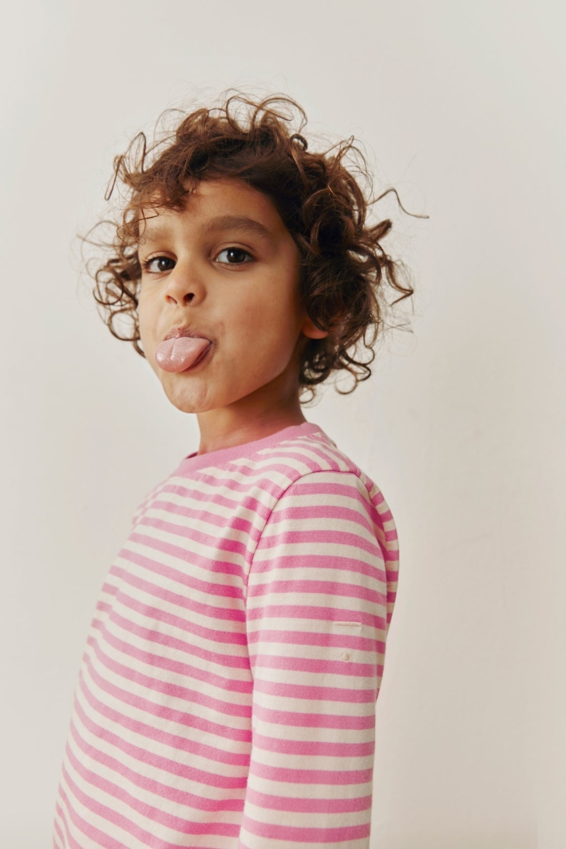 Child wearing a pink and white striped shirt against a plain background