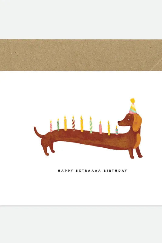 Birthday card with a dachshund illustration holding candles and a party hat, with a brown envelope.