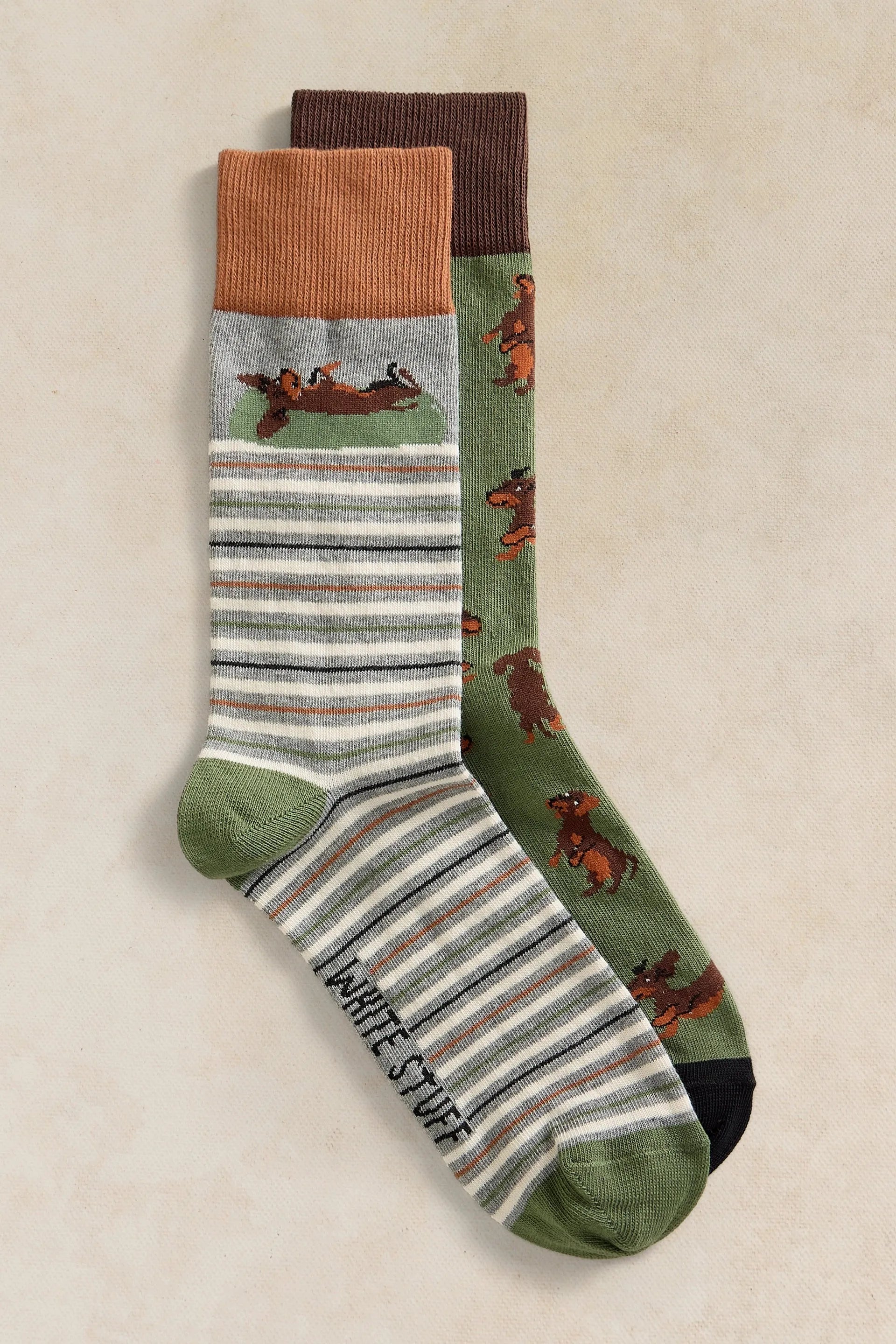 Two pairs of organic cotton socks featuring a dachshund dog pattern on a beige background.