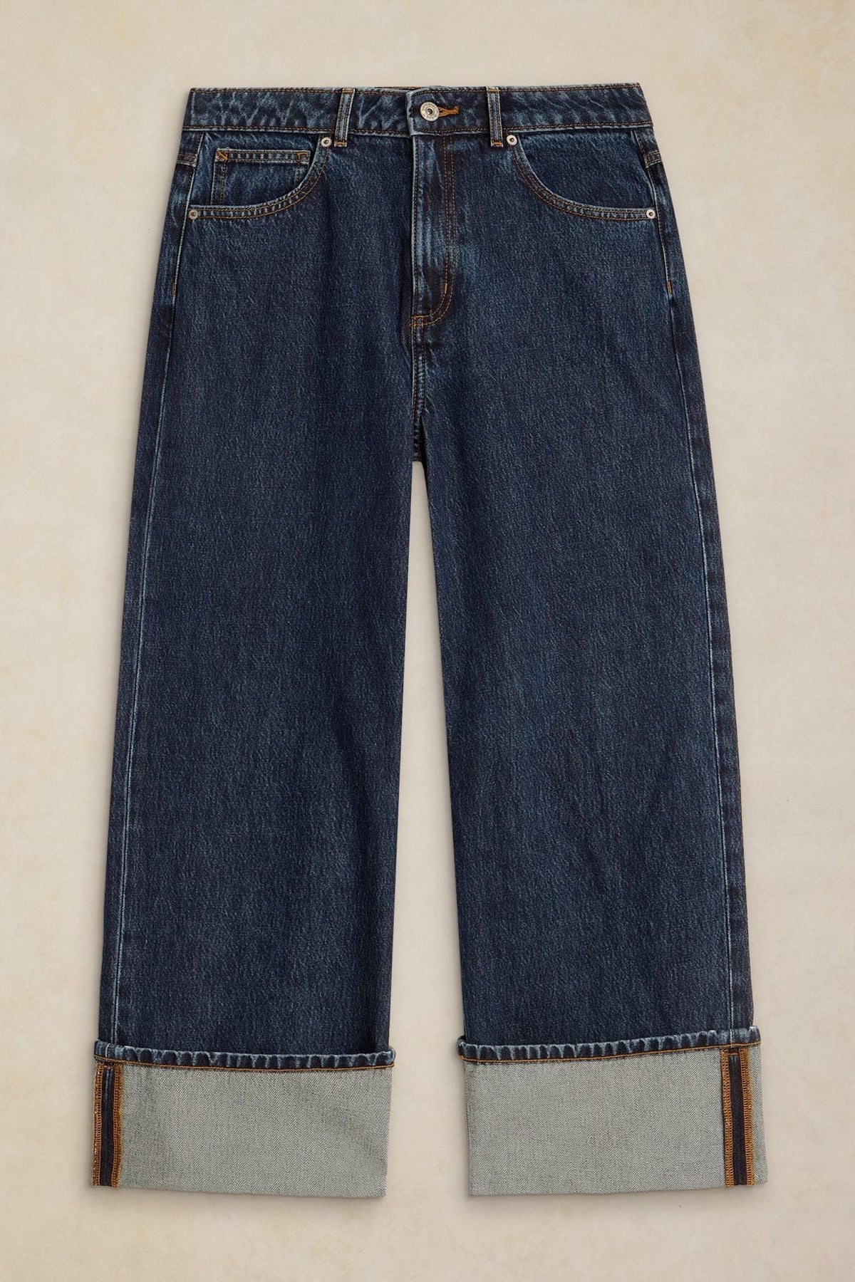 Front view of dark denim women's jeans with wide cuffed hems against a light background.