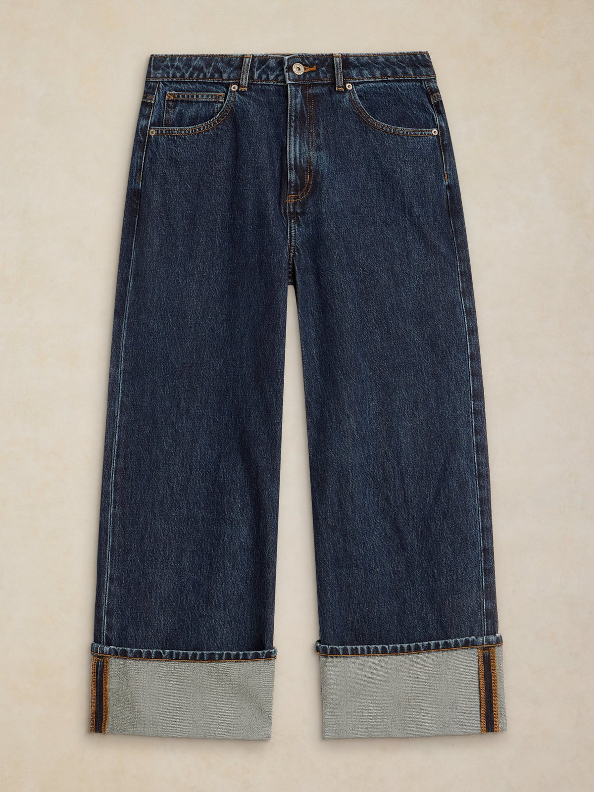 Front view of dark denim women's jeans with wide cuffed hems against a light background.
