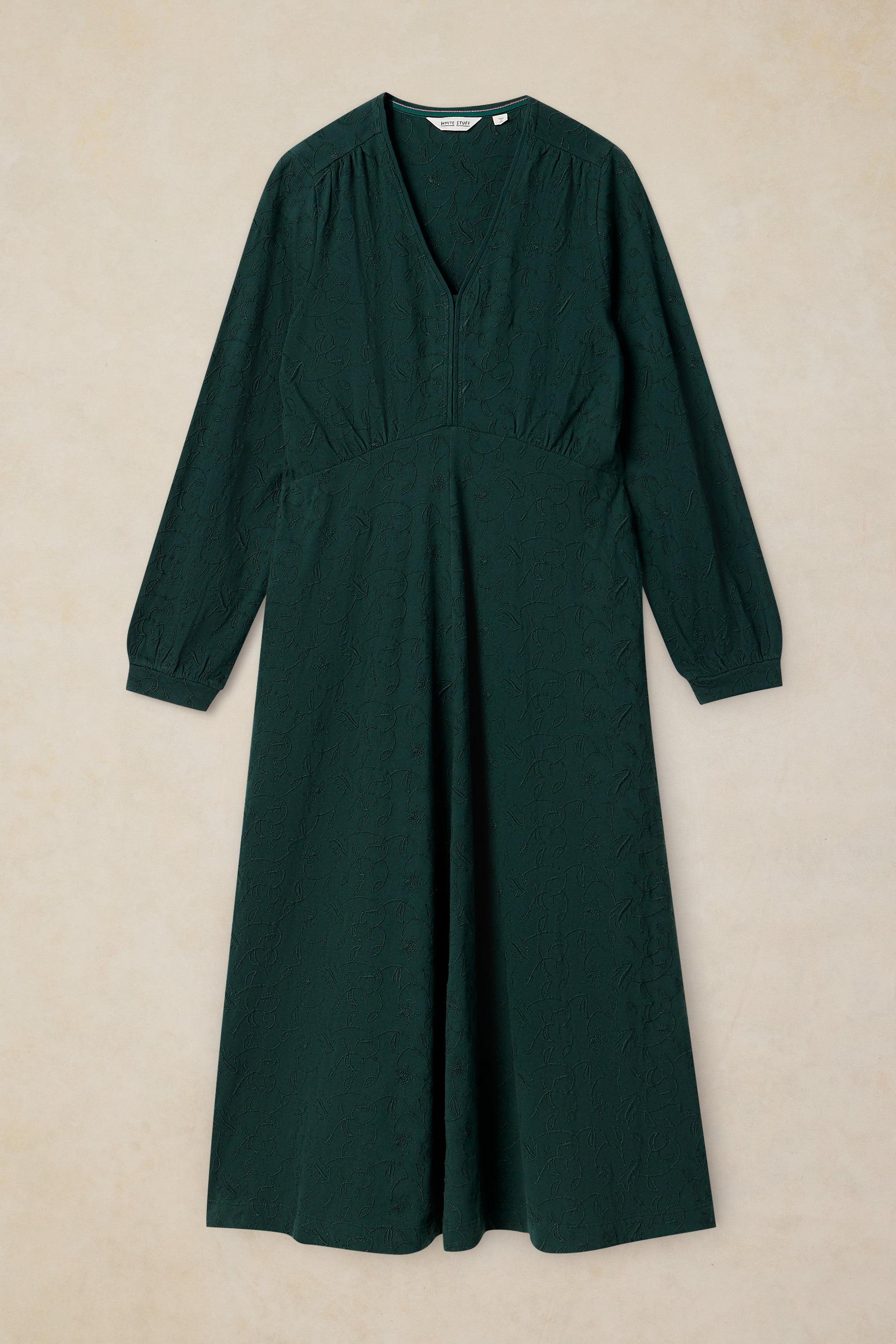 A dark forest green long-sleeve midi dress with a V-neckline and gathered waist, displayed flat against a textured beige background.