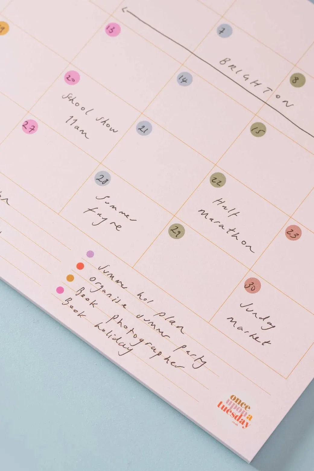 A close-up view of a dateless calendar tear-off pad with handwritten notes for family and work scheduling.