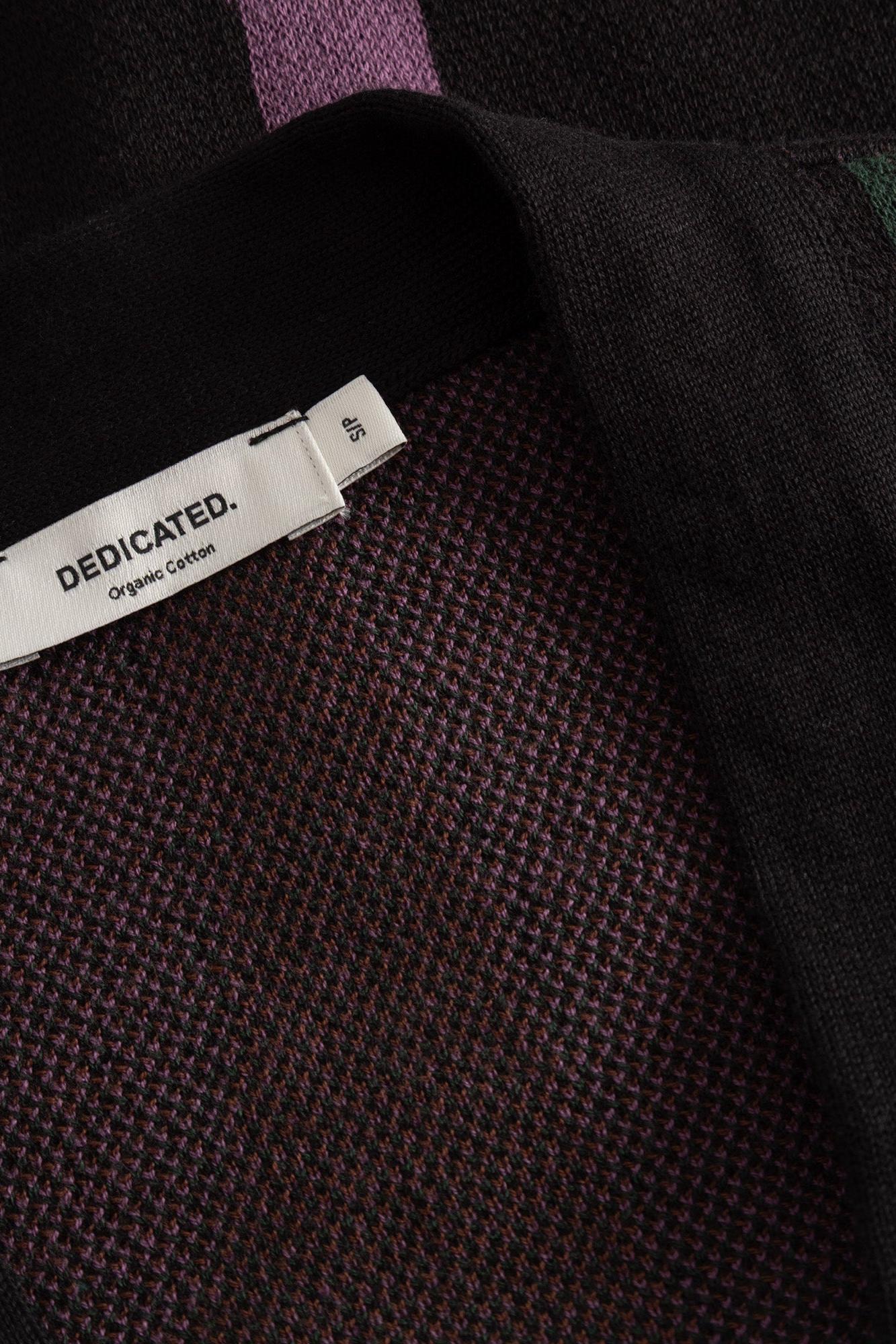 Close-up of a knit garment showing a white fabric label that reads 'DEDICATED. Organic Cotton' sewn onto the inside collar.