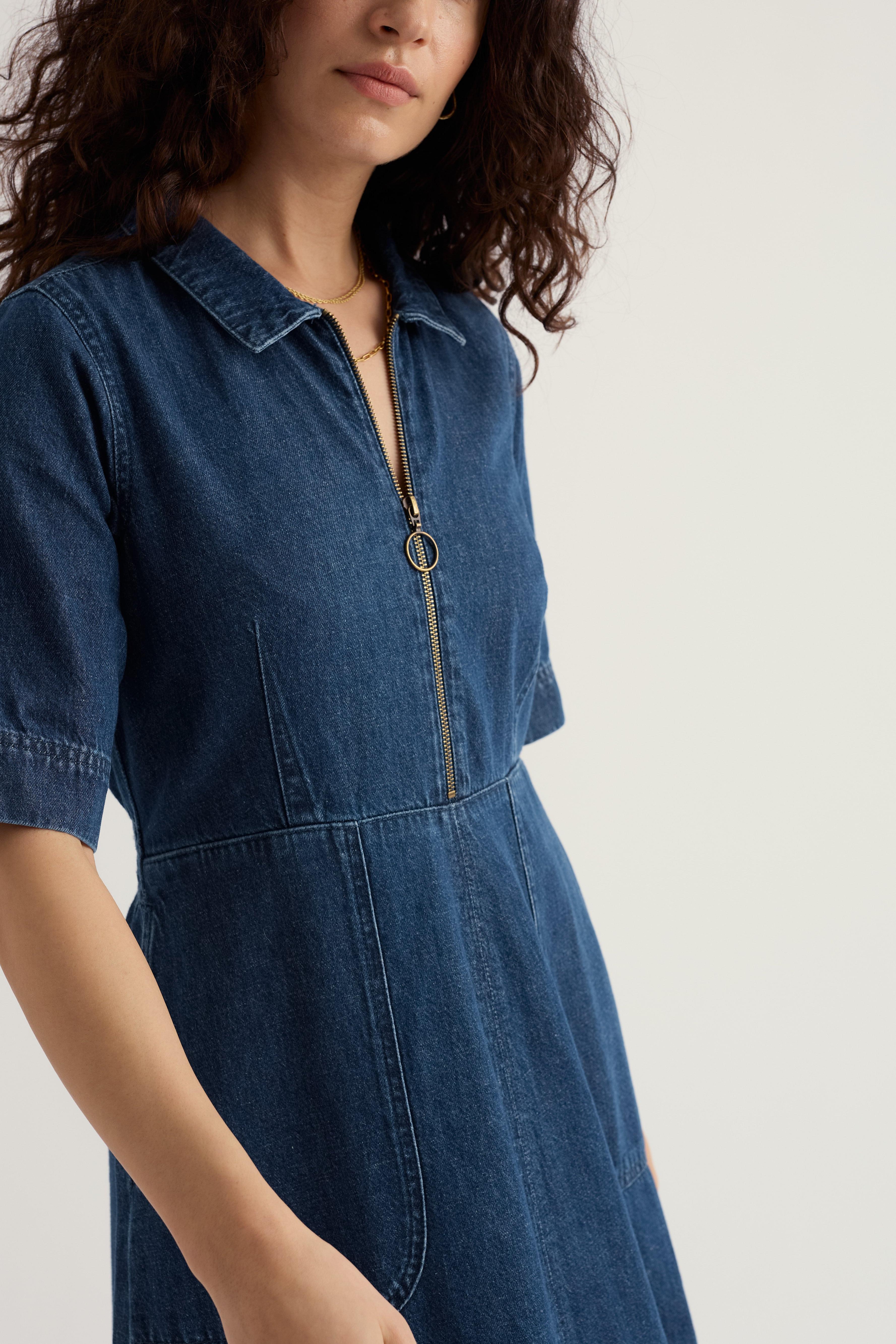 Woman wearing a blue denim dress with a zipper on a light background